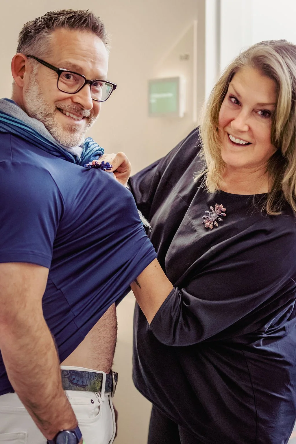 A woman is giving a man a vaccination in his arm, both are smiling.