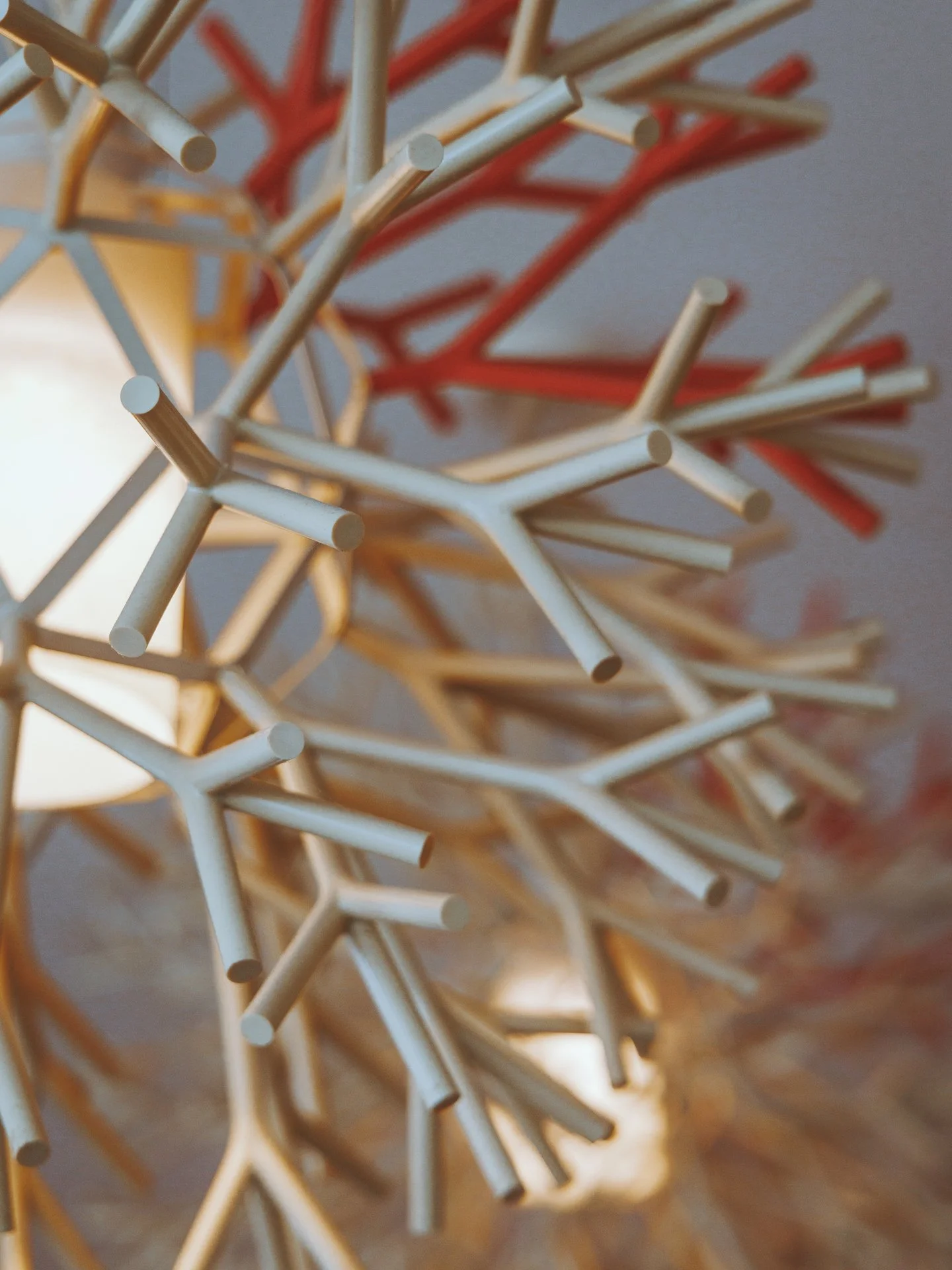 Close-up of a decorative geometric light fixture with white and red parts and a warm glow.