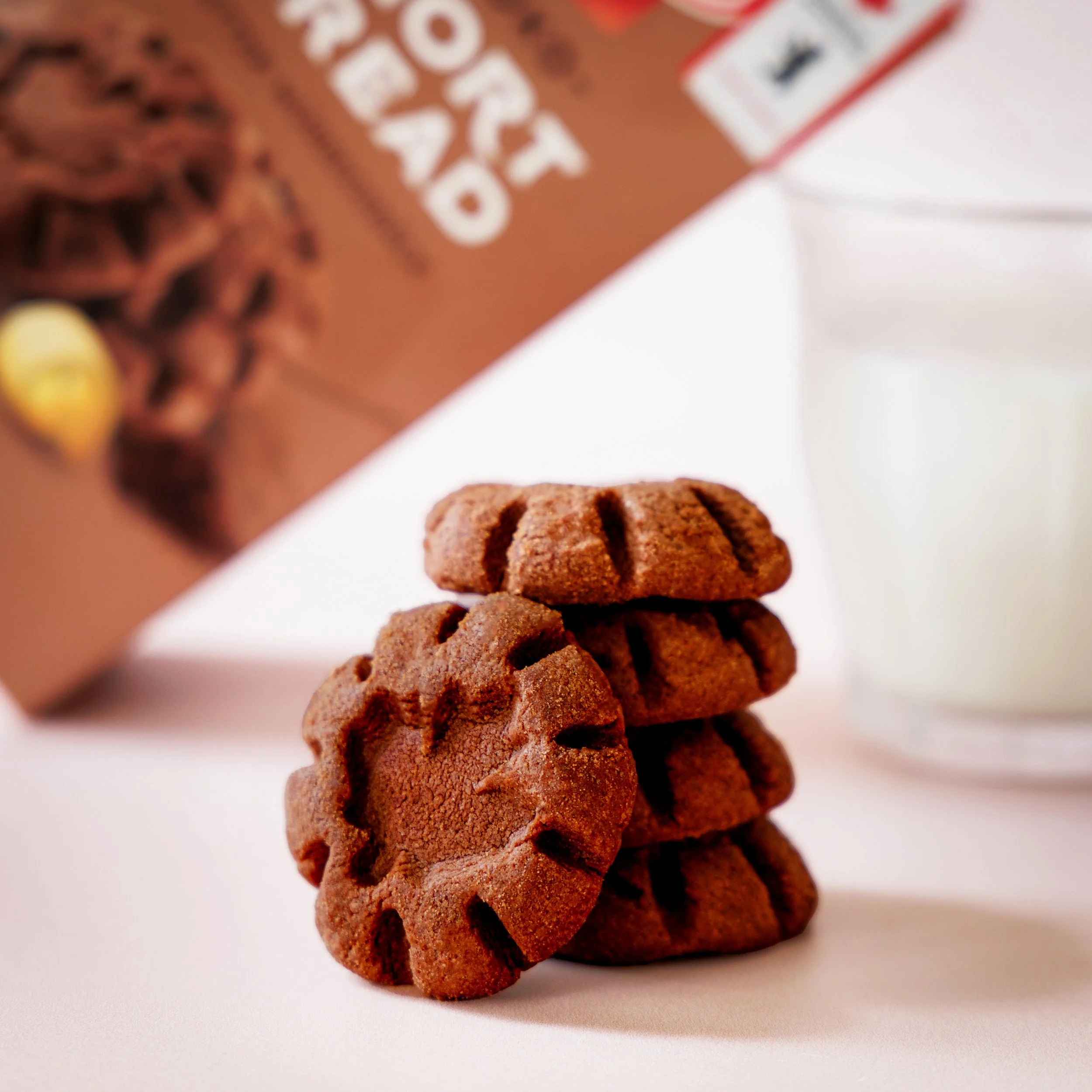 Close-up of stacked chocolate cookies on a white surface with blurred background.