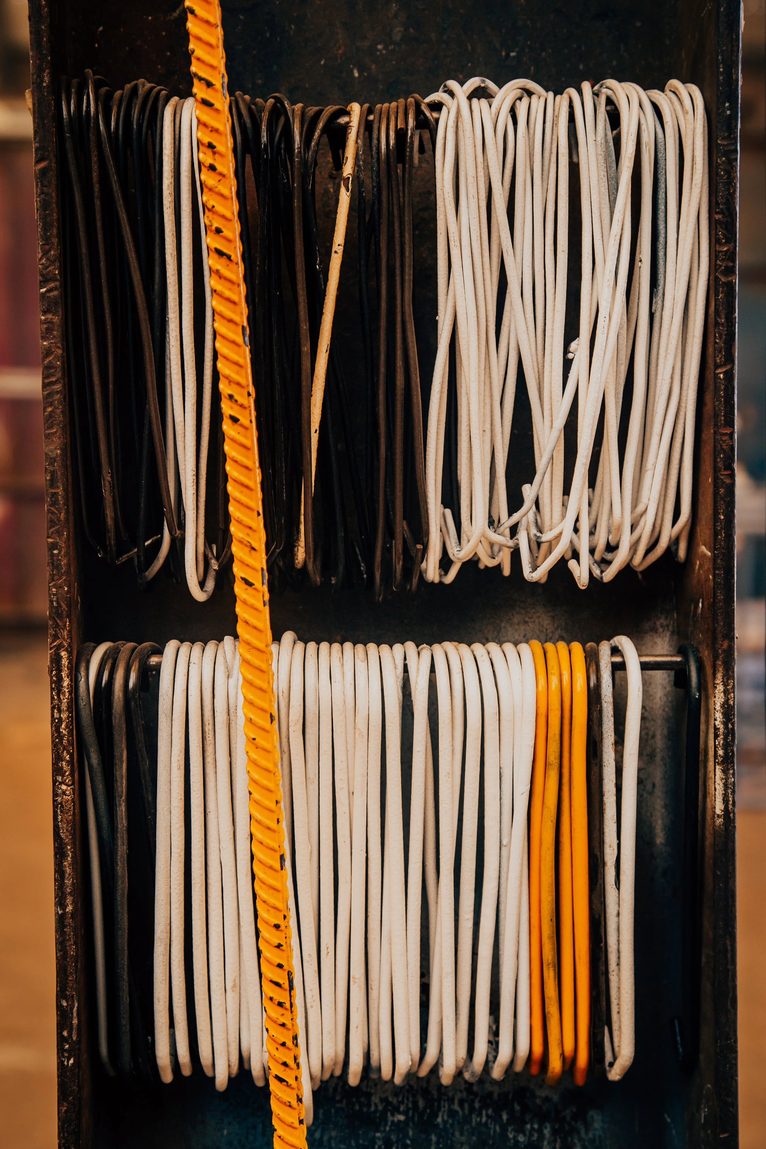 A collection of variously colored and shaped shoelaces organized in a storage container, including black, white, yellow, and patterned laces.