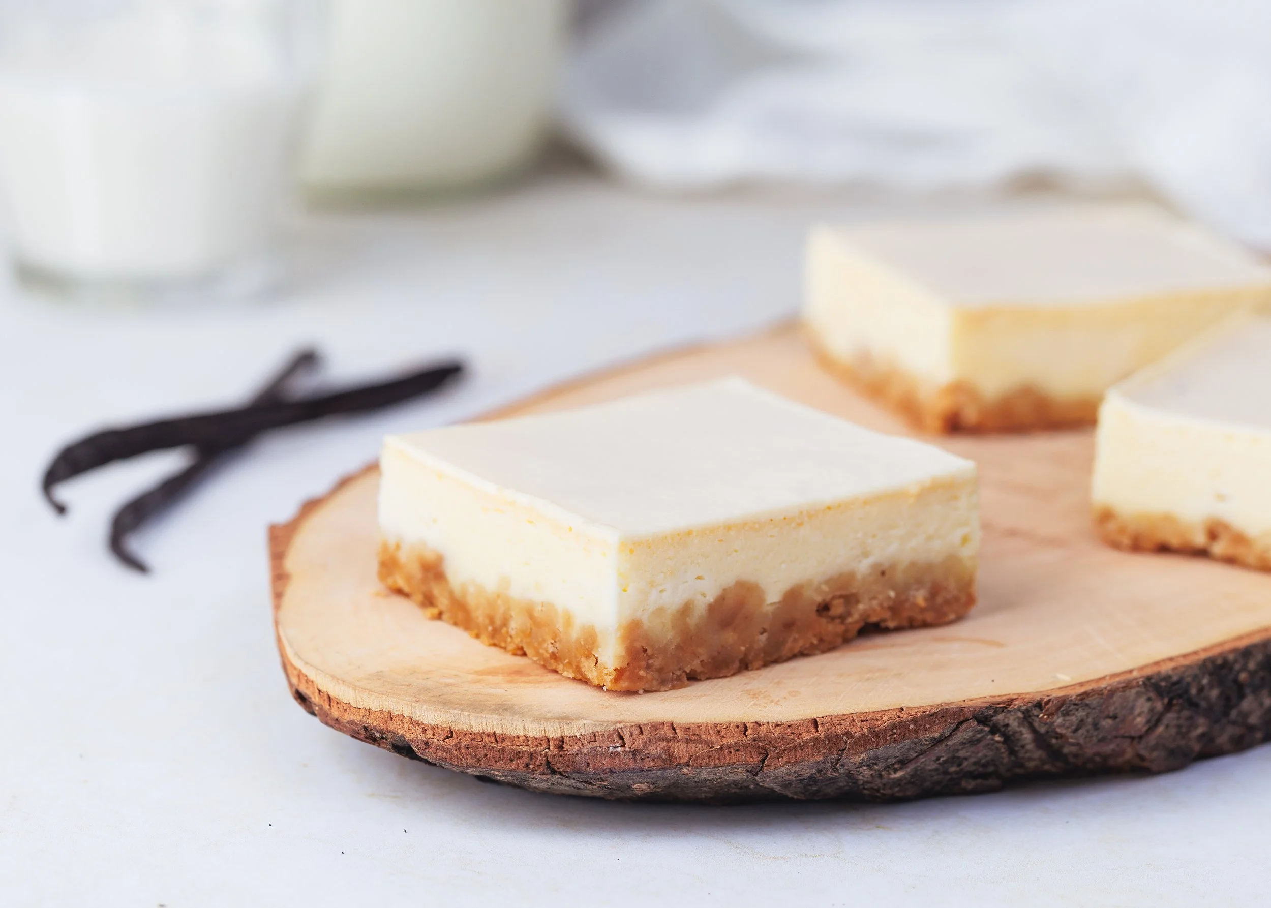 Close-up of a slice of cheesecake on a wooden plate with a blurred background.