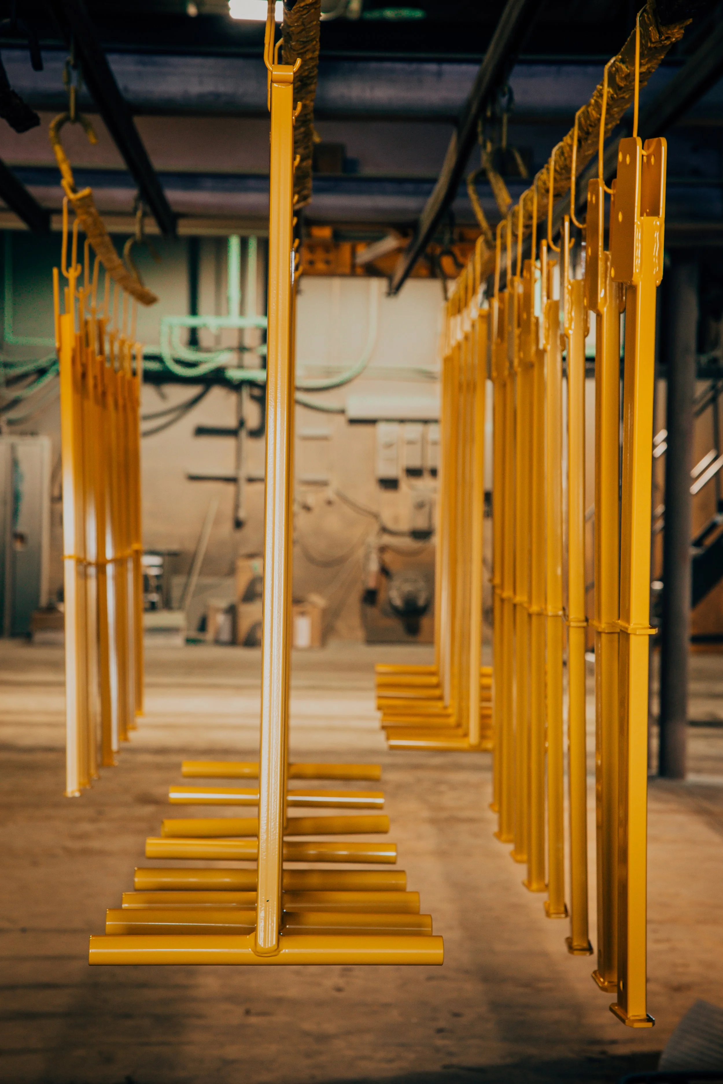 Yellow swing seats hanging in a line in an indoor space with a wooden floor.