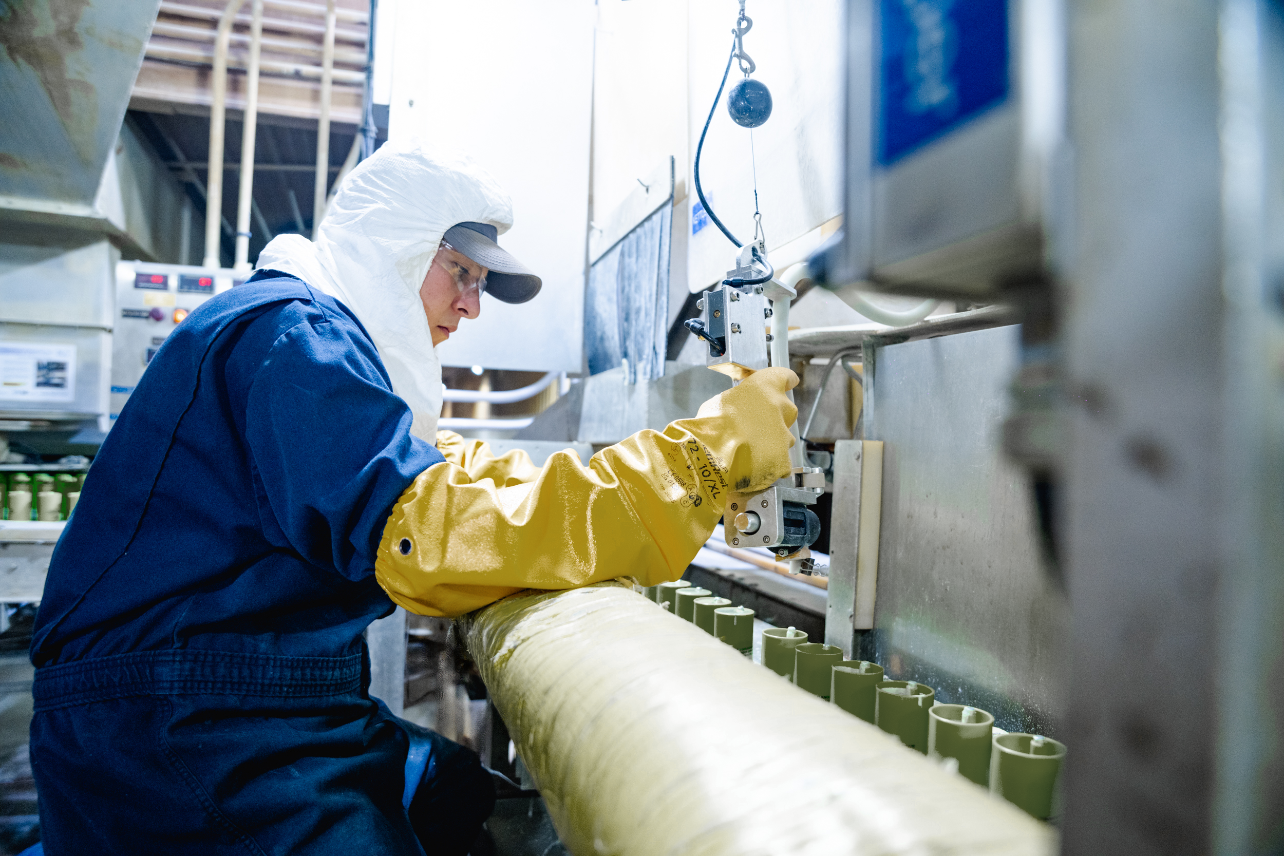 A person in safety gear working on cast booster manufacturing.