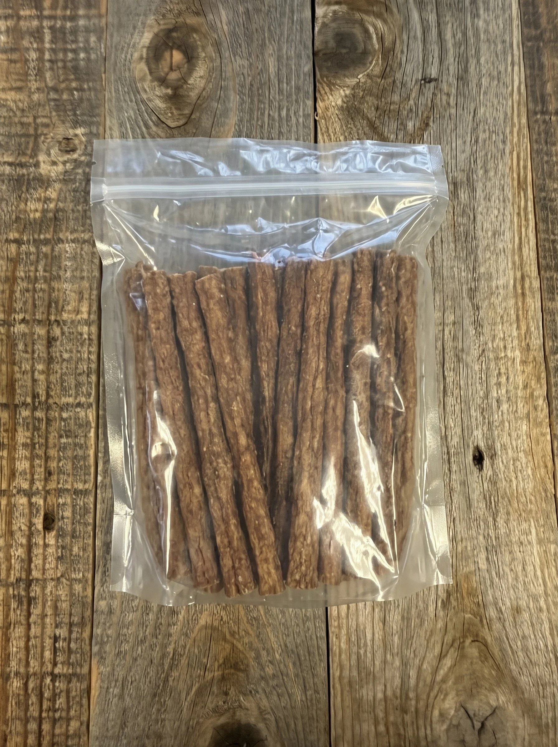 Clear resealable bag filled with brown chicken treats on a rustic wooden table