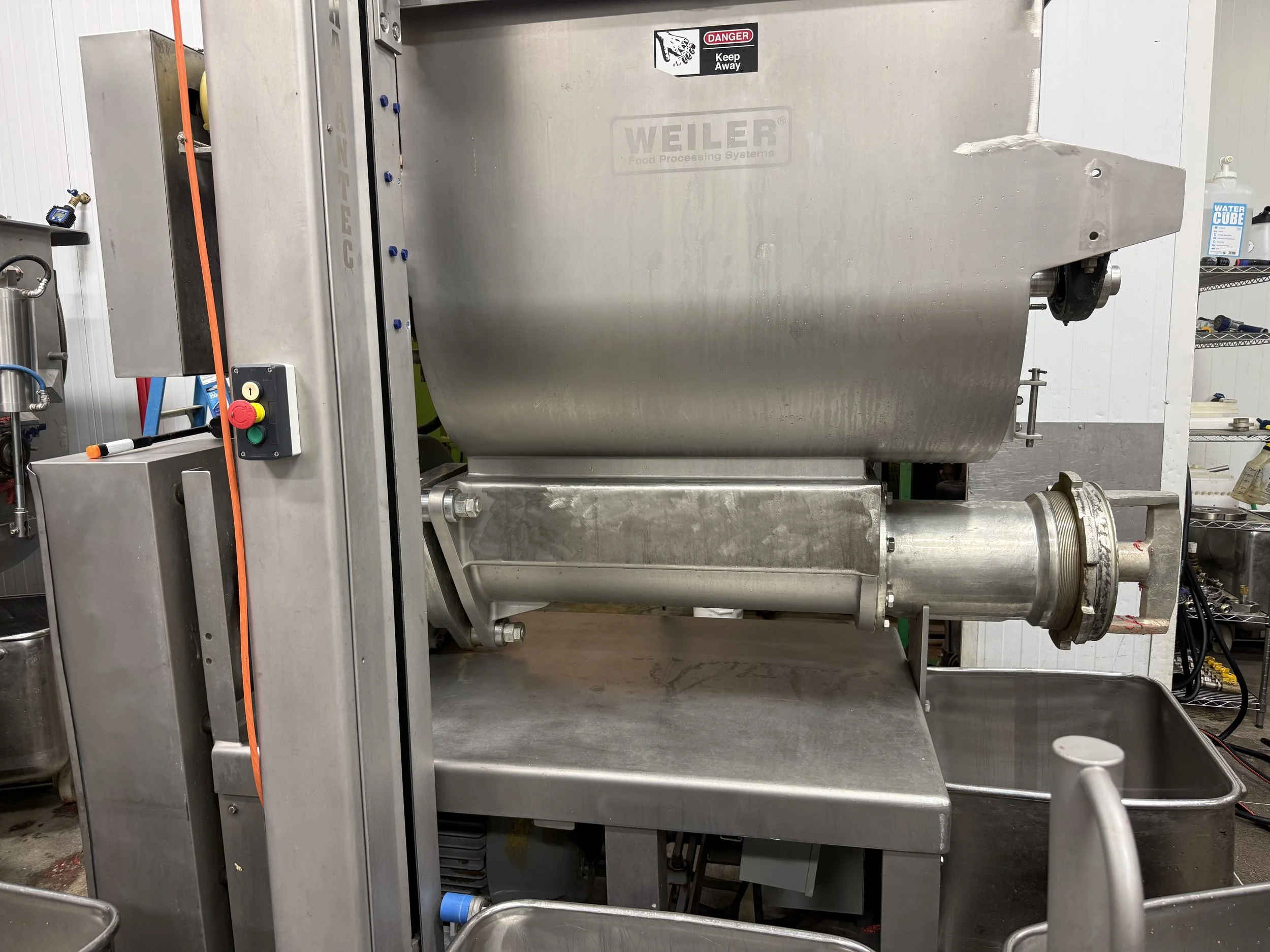Stainless steel Weiler food processing machine with mixing chamber, auger, safety warning, and control panel in an industrial facility