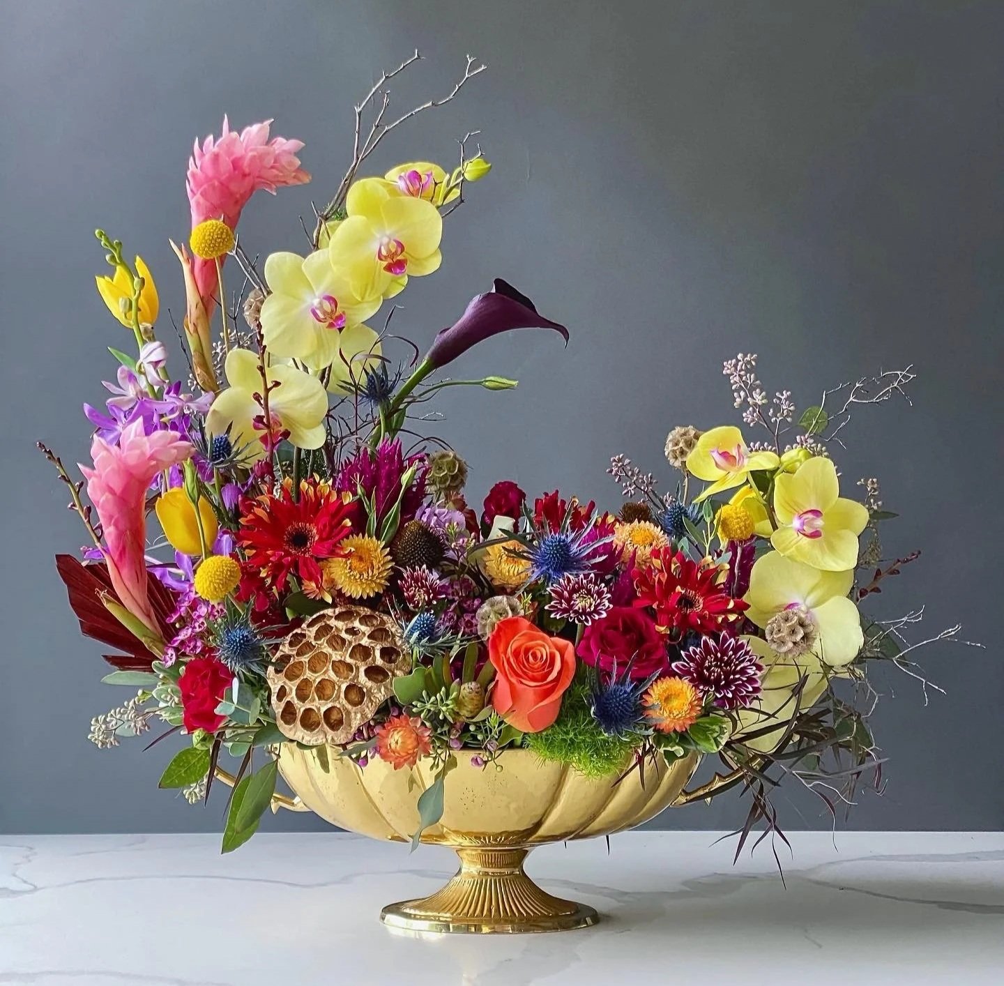 A colorful flower arrangement in a gold basin.