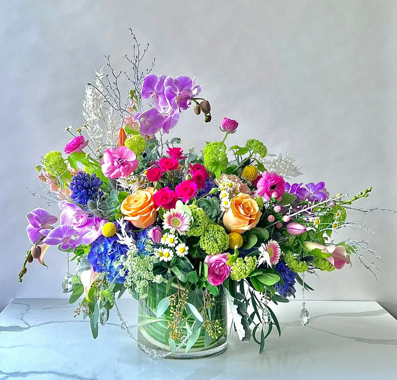 Colorful flower arrangement in a glass vase on a white surface.