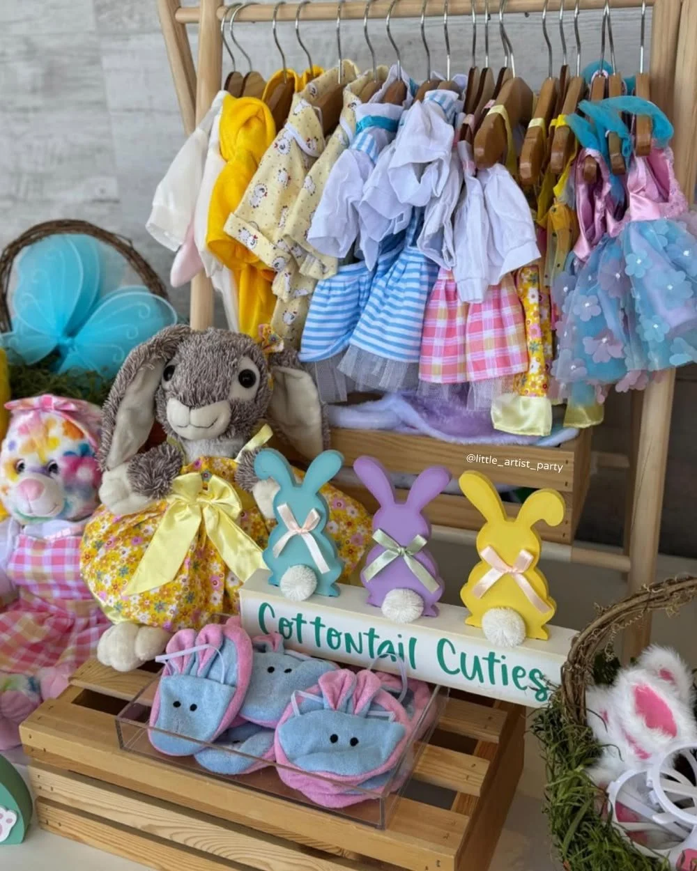 Display of colorful children's clothing, plush bunny toys, and decorated bunny-shaped items at a craft or gift shop.