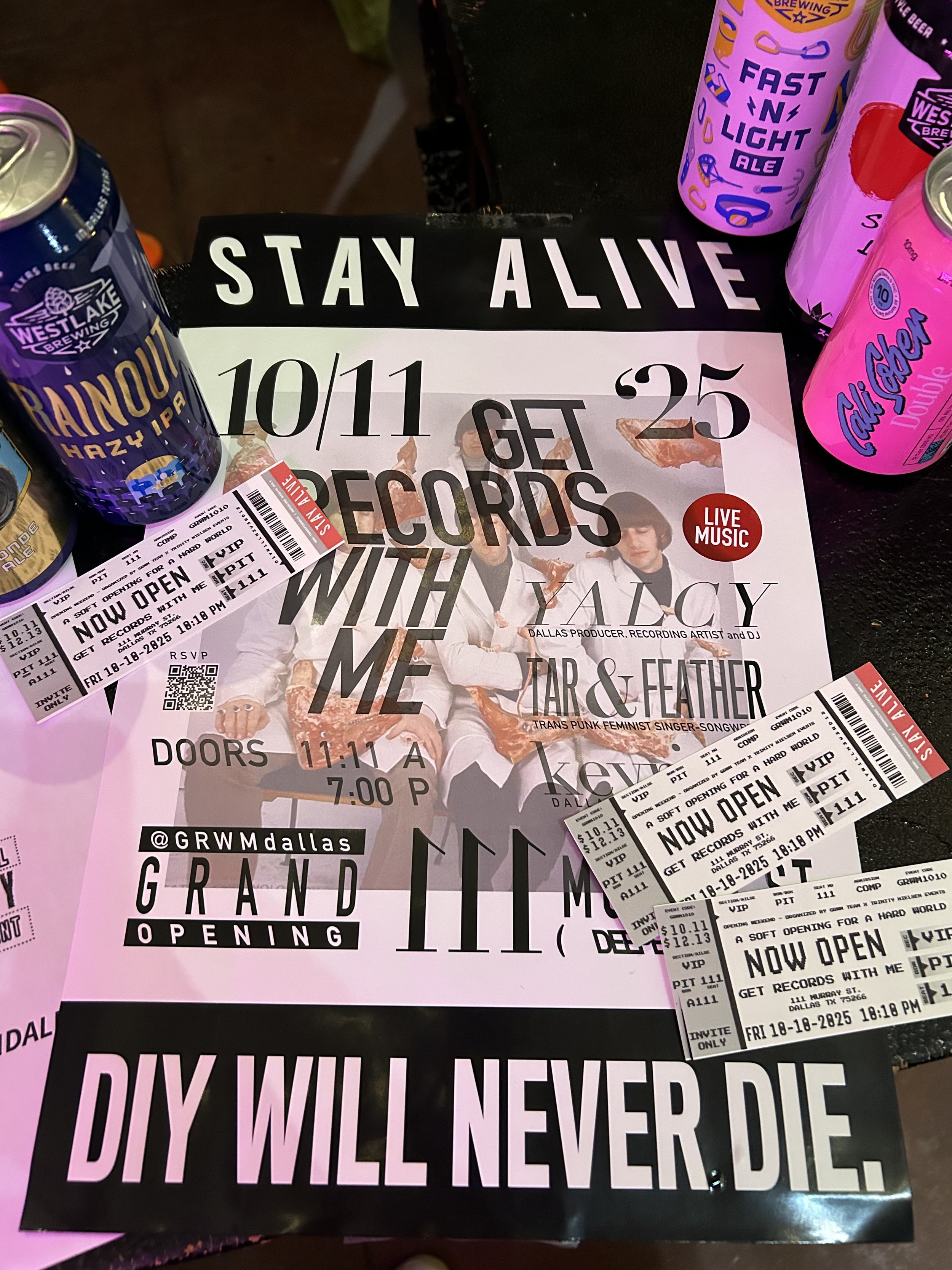 A collection of concert tickets, promotional flyers, and beverage cans on a dark surface. The flyers and tickets promote a music event featuring Yalcy, with details about the date, time, and location. The cans are from Westlake Brewing and feature colorful designs.