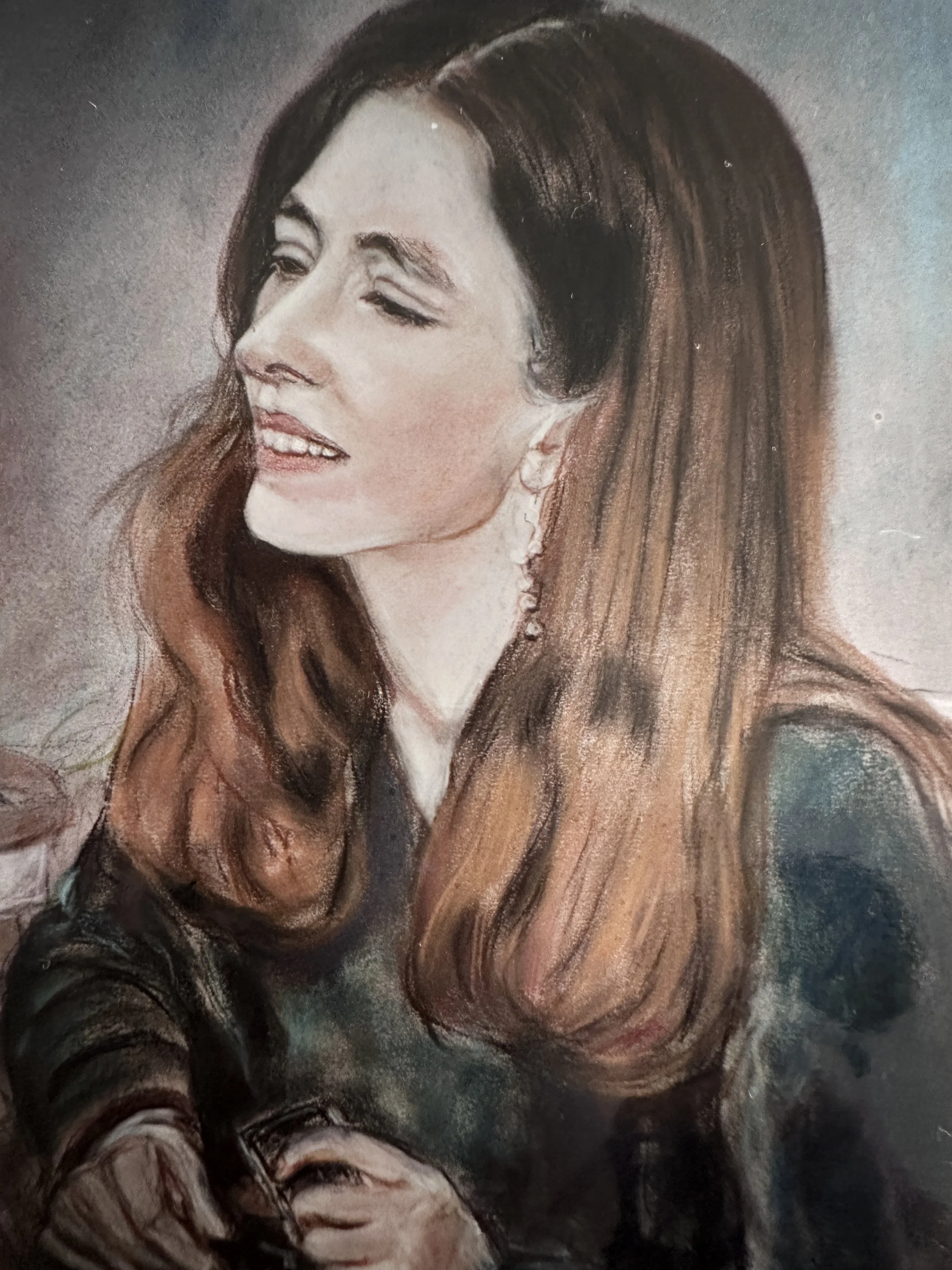 A woman with long brown hair and earrings, with a focused expression, appears to be painting or drawing.