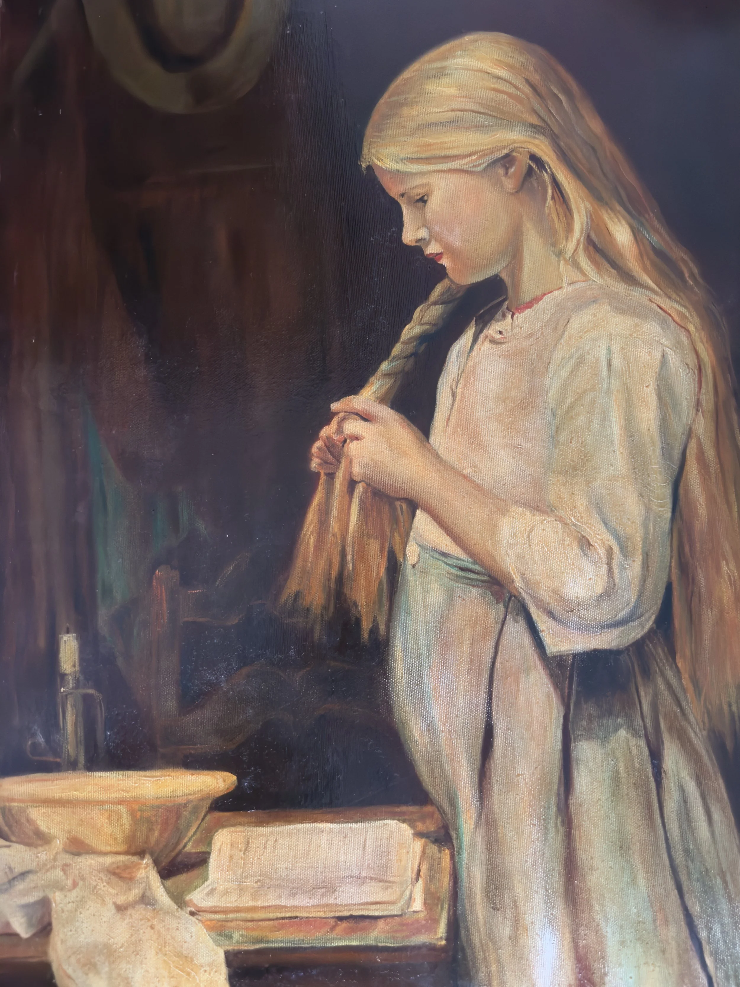 A young girl with long blonde hair and a red necklace is seen looking down and holding a small object in her hands. She is standing next to a table with various objects, including a bowl, a block, and some crumpled paper. The background is dark, emph