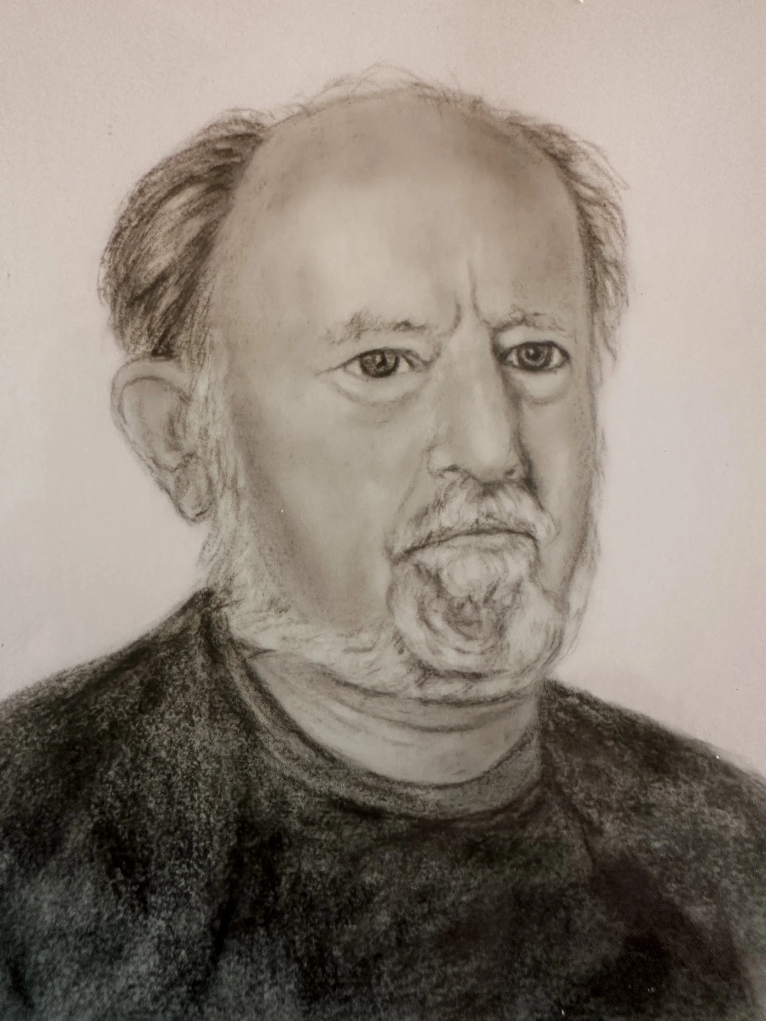 A detailed pencil sketch of an elderly man with a serious expression, short gray hair, and a beard. He is wearing a patterned shirt.