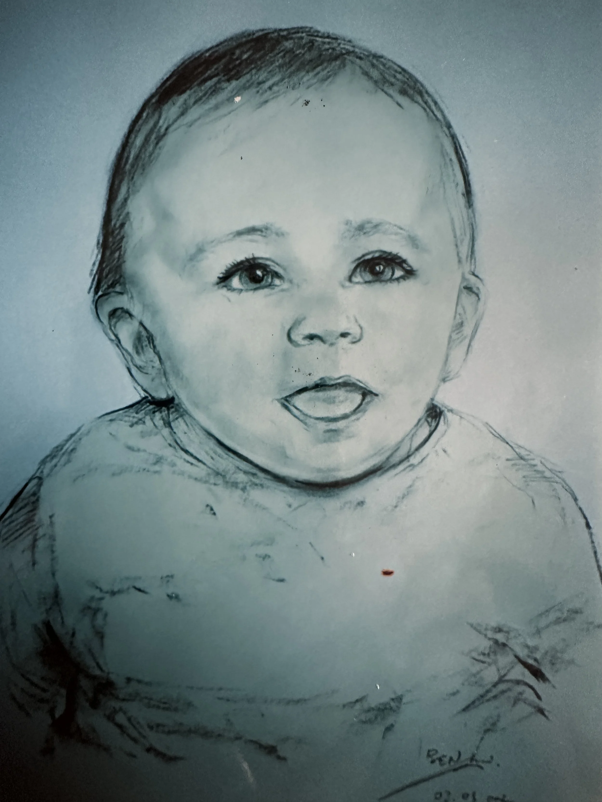 A pencil sketch of a baby's face with detailed eyes, nose, mouth, and hair, signed at the bottom right corner.
