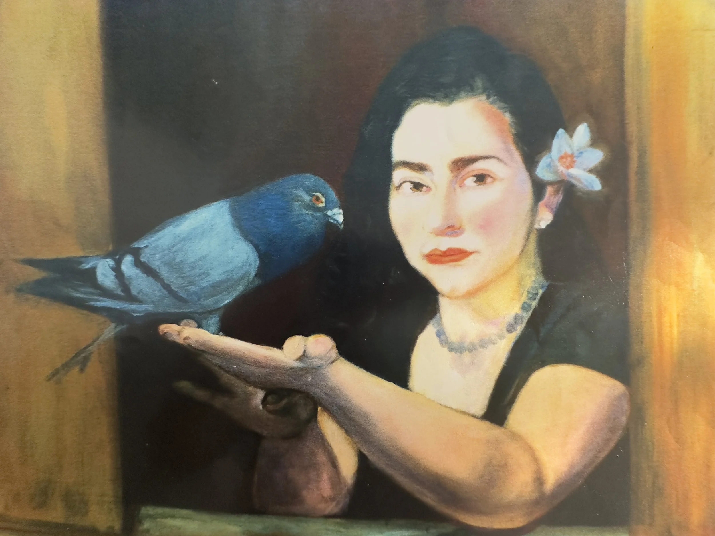 A woman with dark hair and makeup, wearing a black top, has a blue bird perched on her side and a white flower in her hair, set against a warm-toned background.