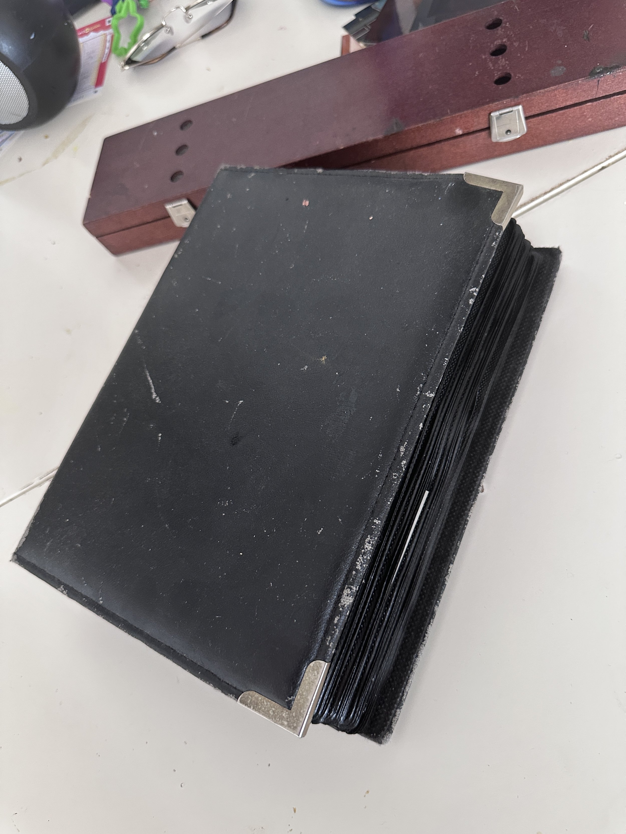 Stack of black zippered cases on a white surface, with a red wooden organizer and miscellaneous items in the background.