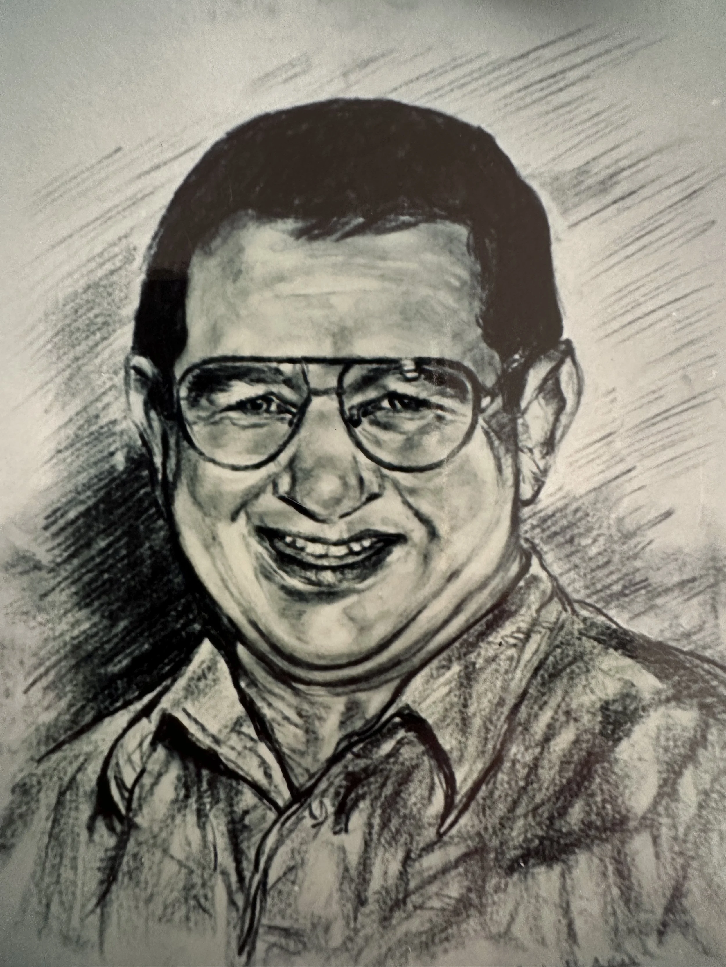 A black and white sketch of a smiling man with glasses, short hair, and wearing a collared shirt.