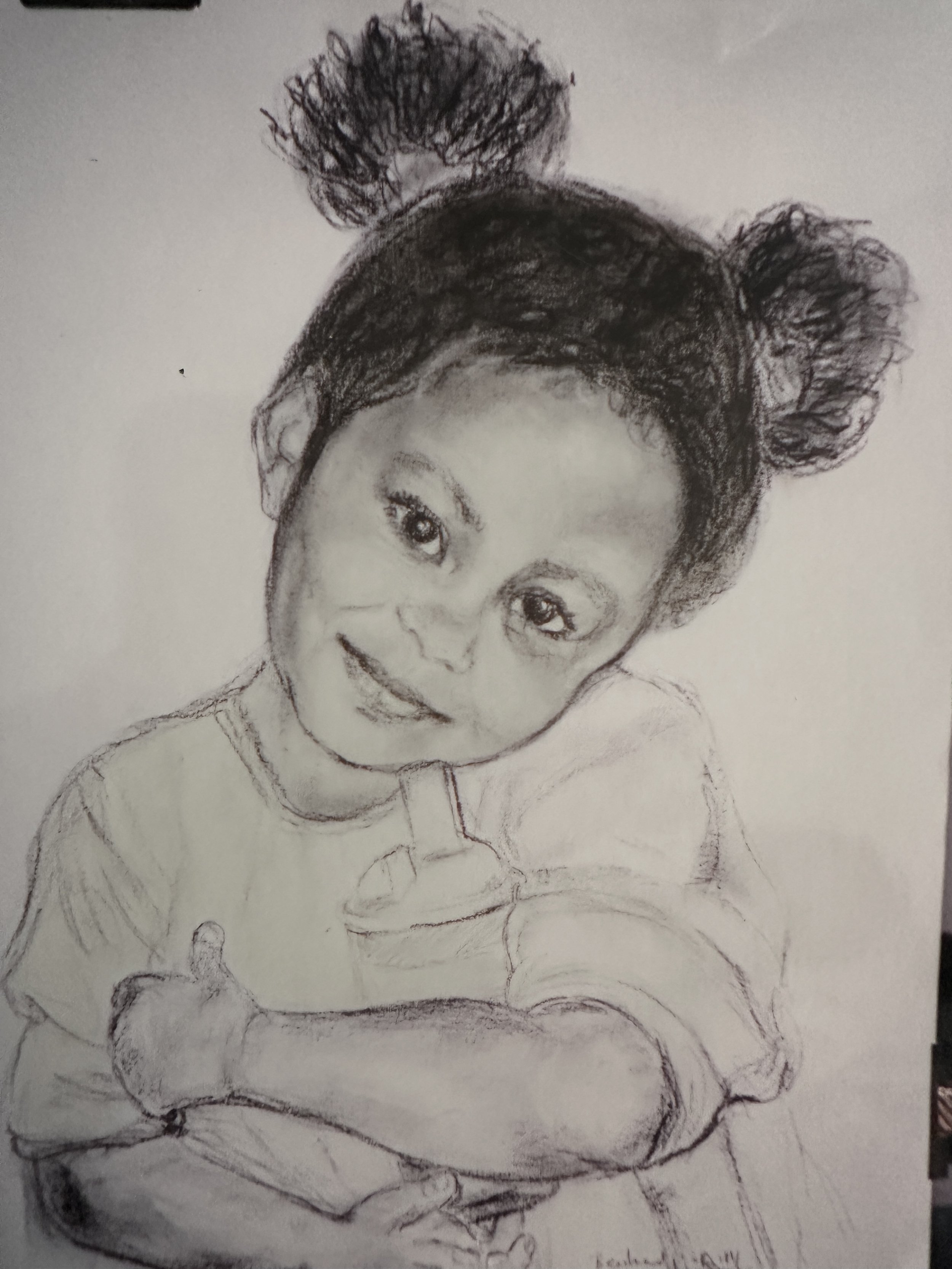 A pencil sketch of a young girl sitting on a chair, smiling, with her hair styled in two buns with curly puffs on top, wearing a short-sleeved top and shorts.
