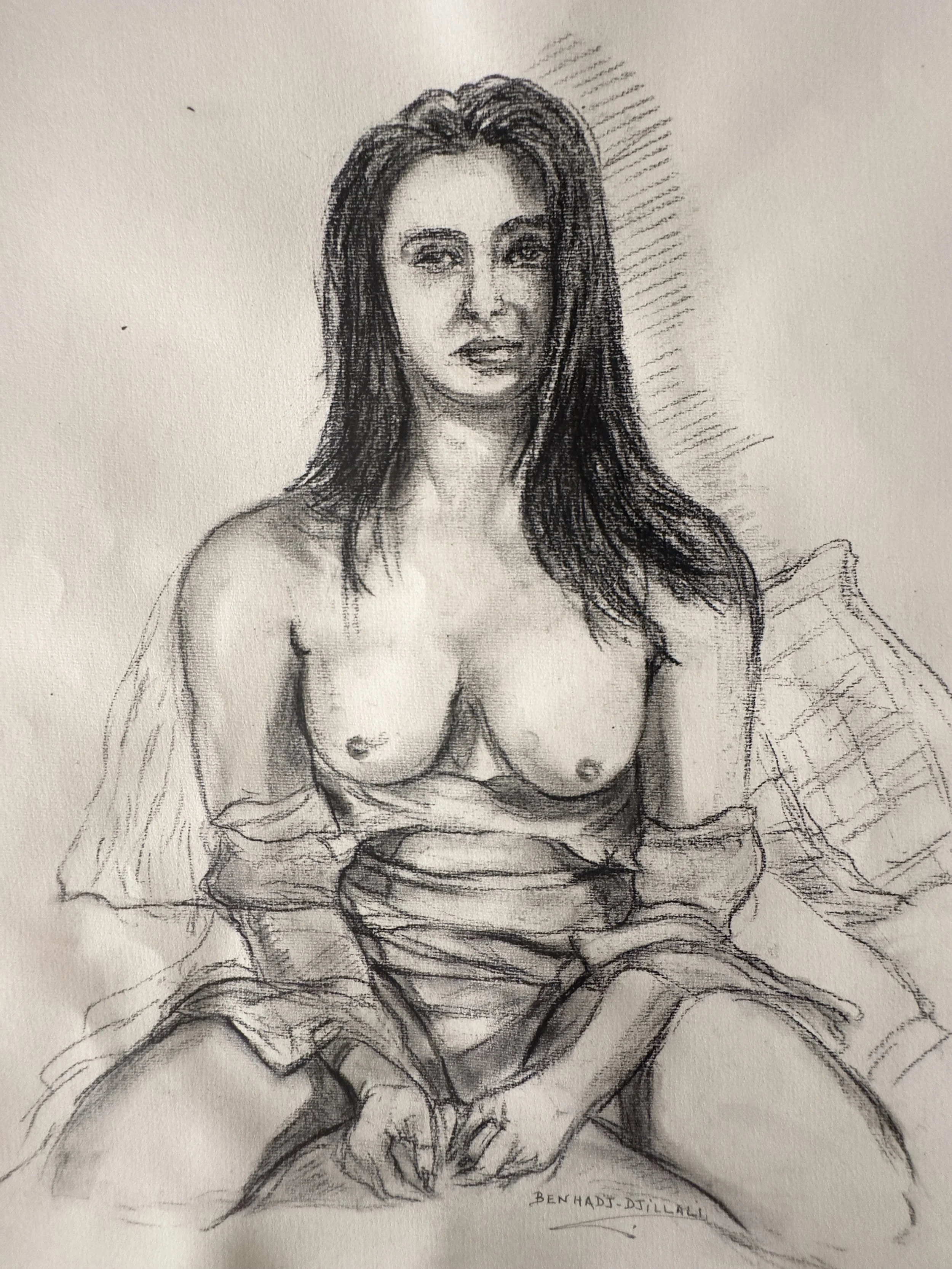 A black and white sketch of a woman sitting cross-legged on a bench or cloth, wearing a loose garment, with long hair and a serene expression, with additional sketch lines indicating background and details.