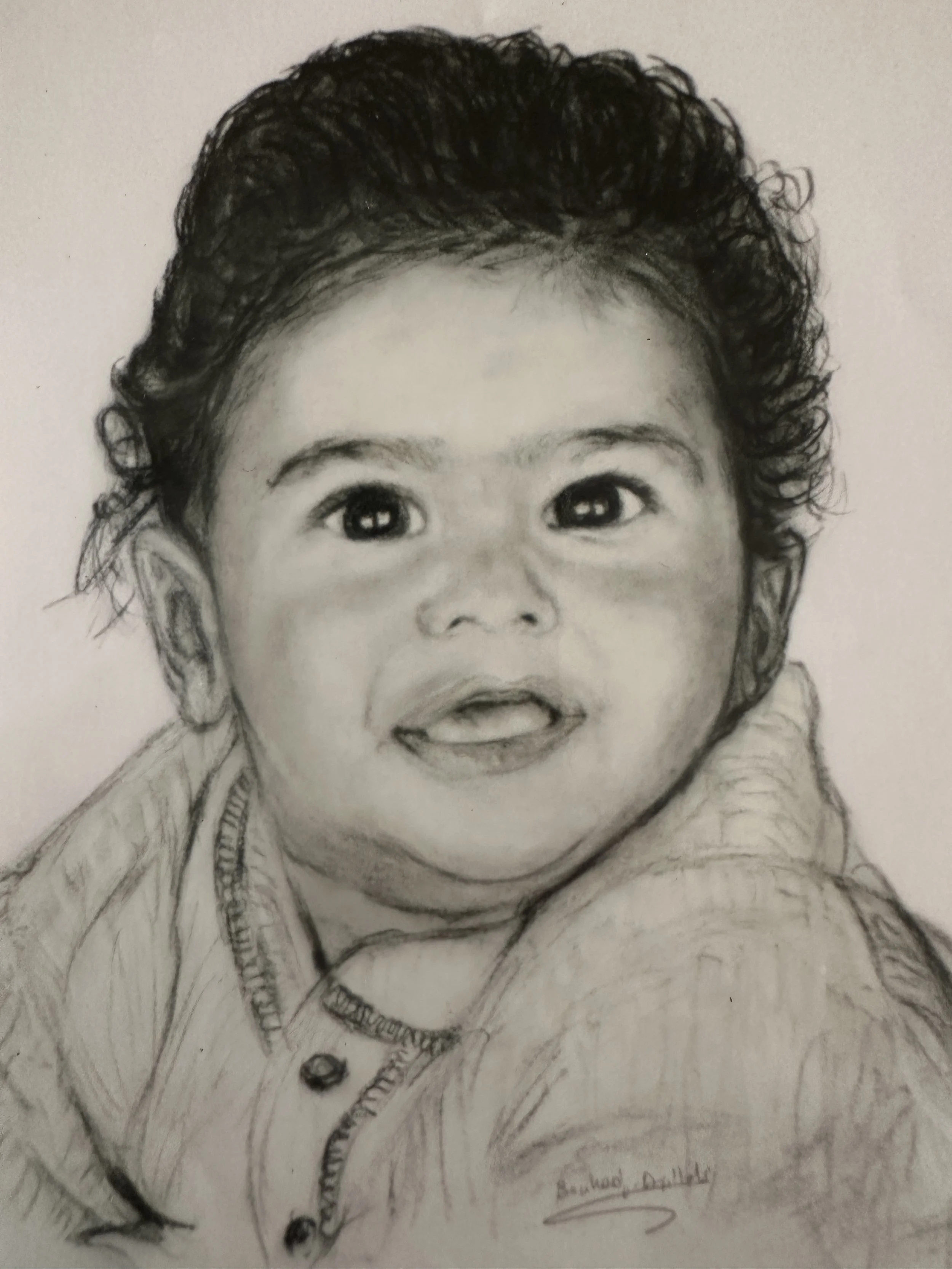 A detailed pencil sketch of a smiling baby's face, with visible curly hair and wearing a hoodie.