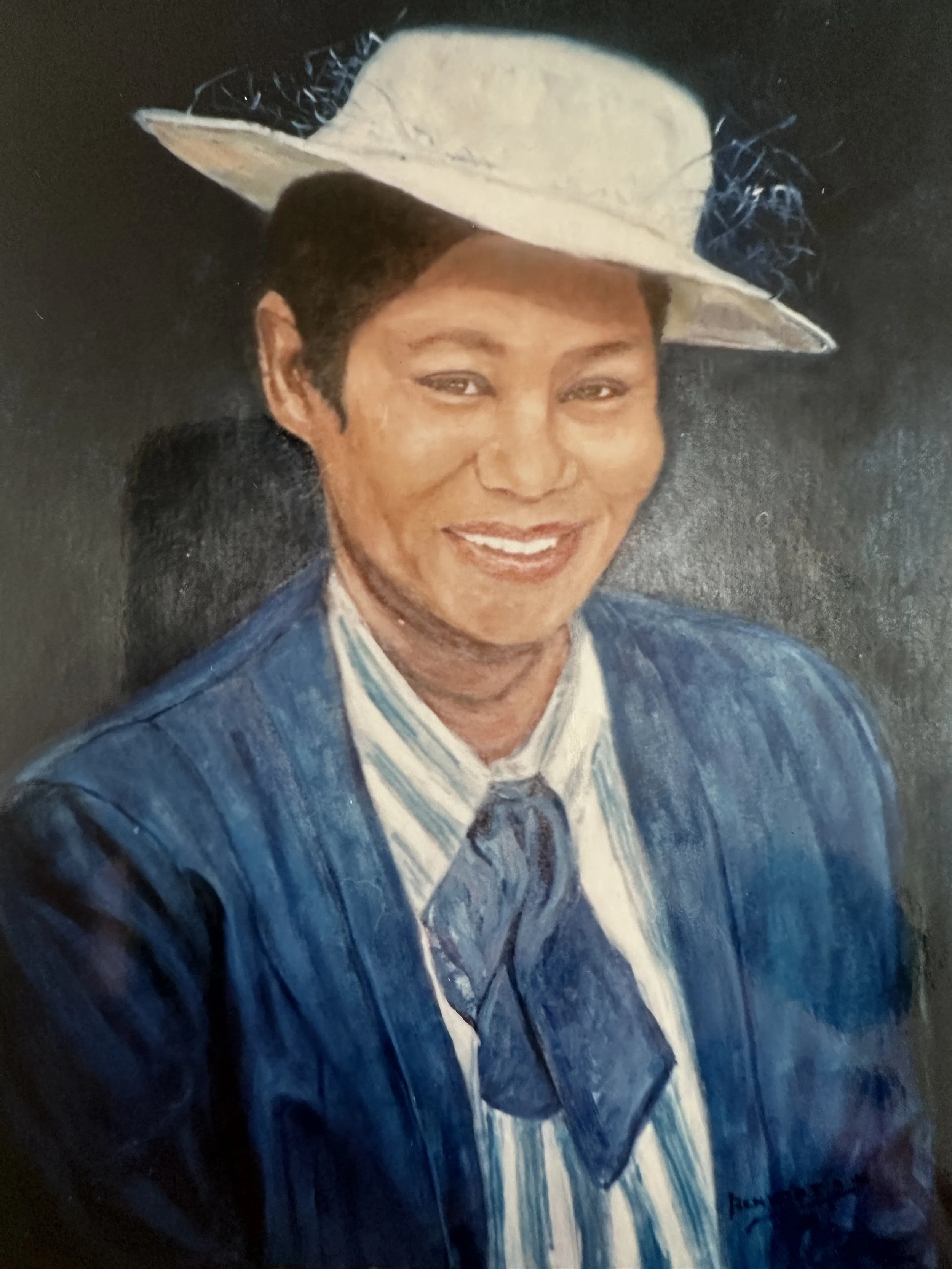 Painting of a smiling woman with short dark hair, wearing a blue suit, white shirt, and blue tie, with a white hat decorated with a black feather and blue ribbon.