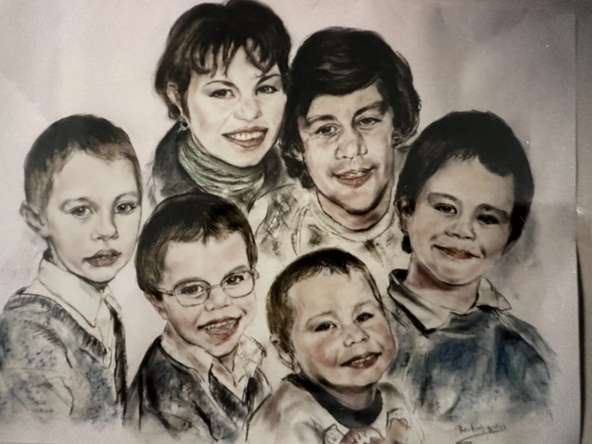 A group photo of several people, including women and children, with diverse facial expressions and hairstyles, all looking towards the camera.