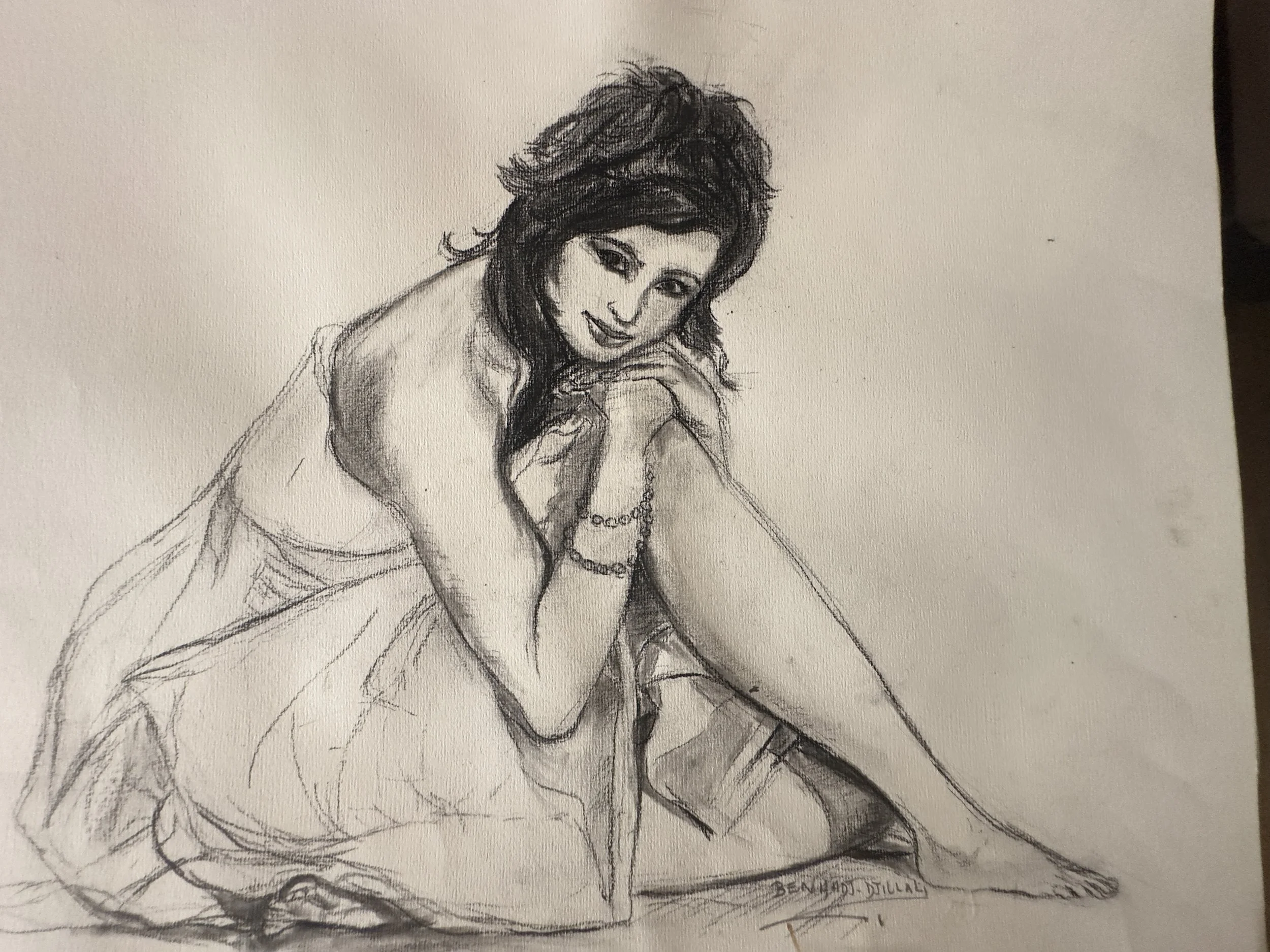 A black and white sketch of a woman with voluminous hair, sitting with one leg crossed over the other, smiling, with her chin resting on her hand. The drawing is signed by Beniamino Dilli.