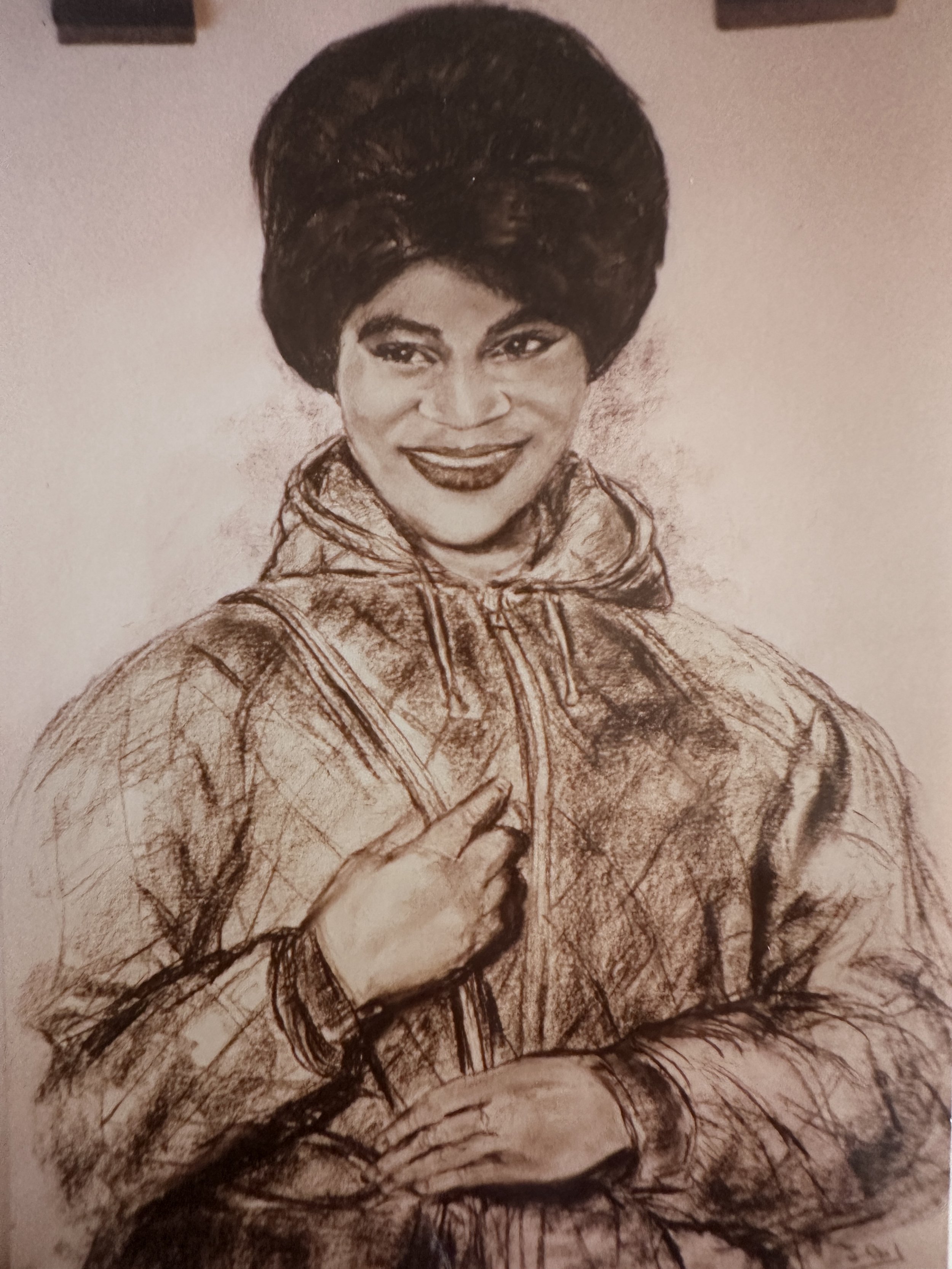 A sketch of a woman with an elaborate hairstyle, smiling and wearing a jacket with a hood.