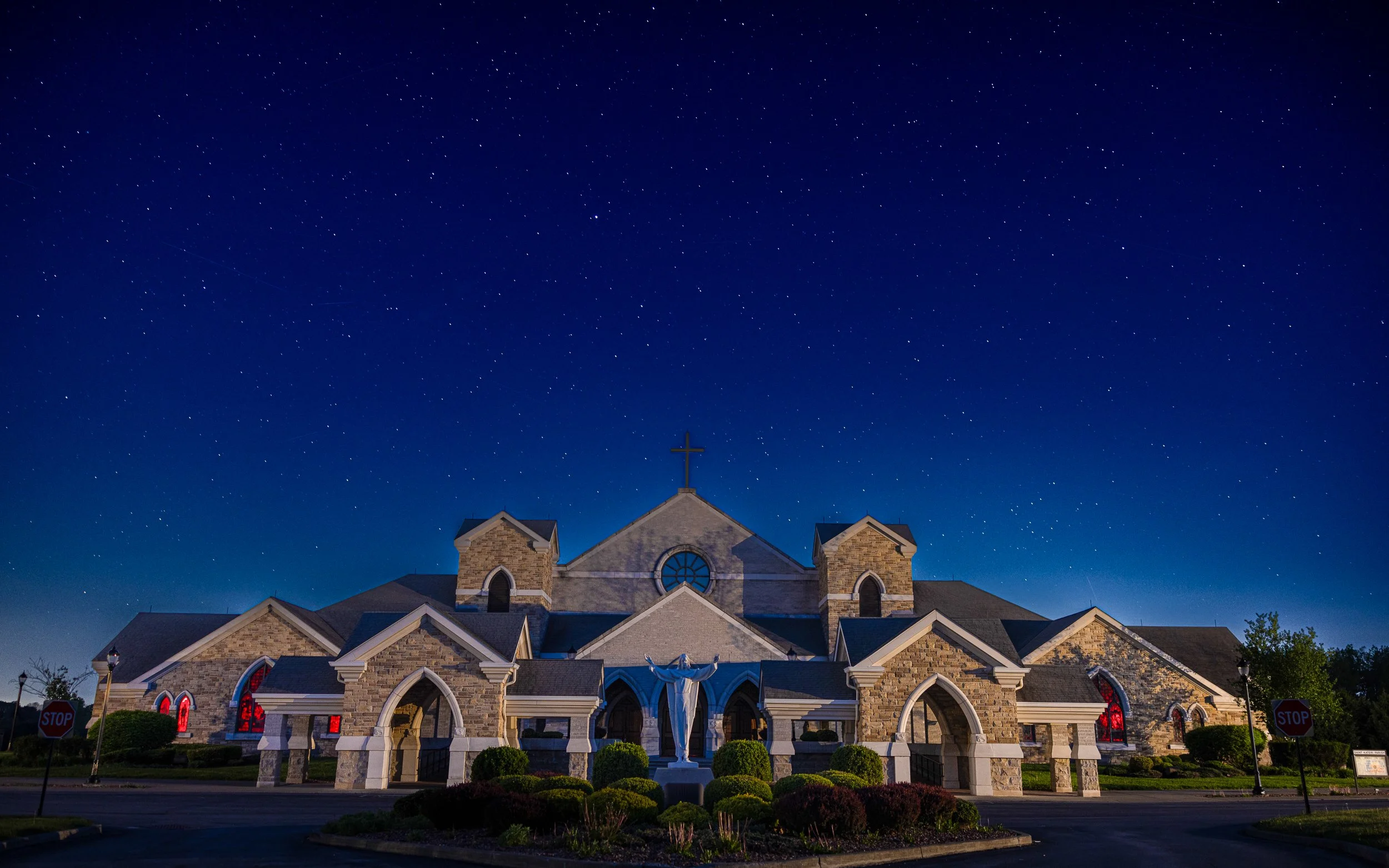 Church at night with an illuminated cross, stained-glass windows