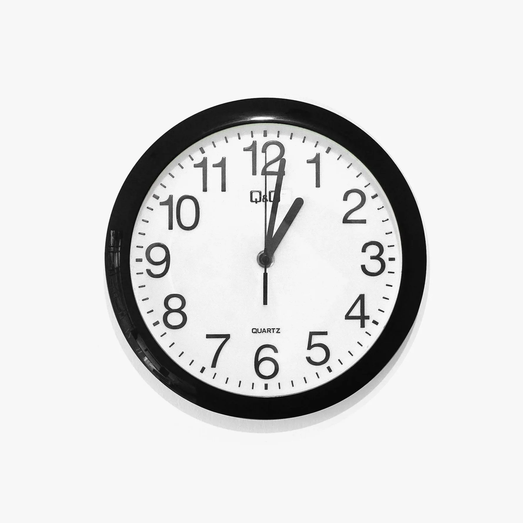 A round wall clock with a black frame, white face, black numbers, and black hands, showing the time 1:00, symbolizing the late night strike couples, florists, and planners can avoid by renting candles from Colorado Candle Studio.