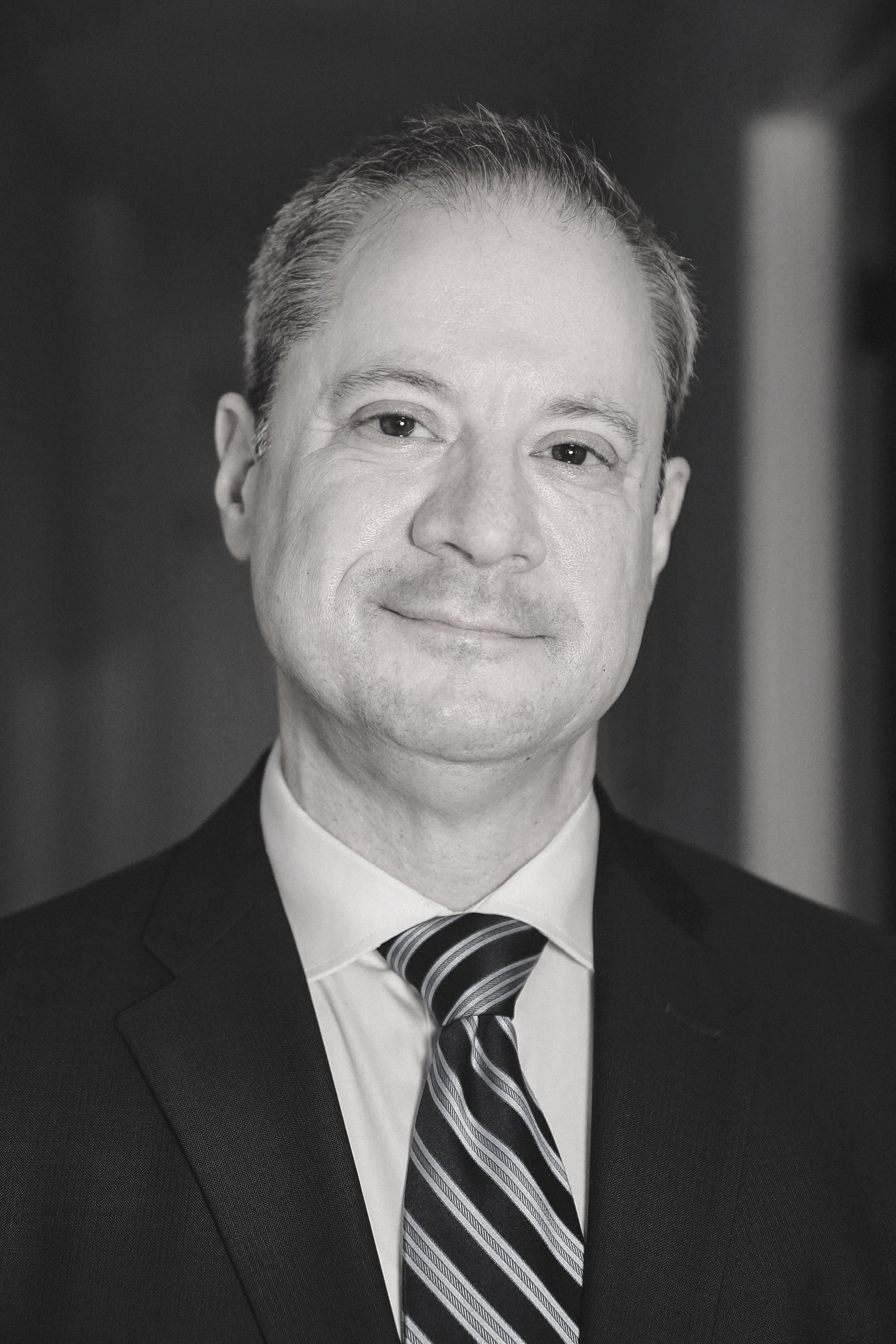 Black and white portrait of Dr. William Berger wearing a suit, tie, and white shirt, smiling softly.