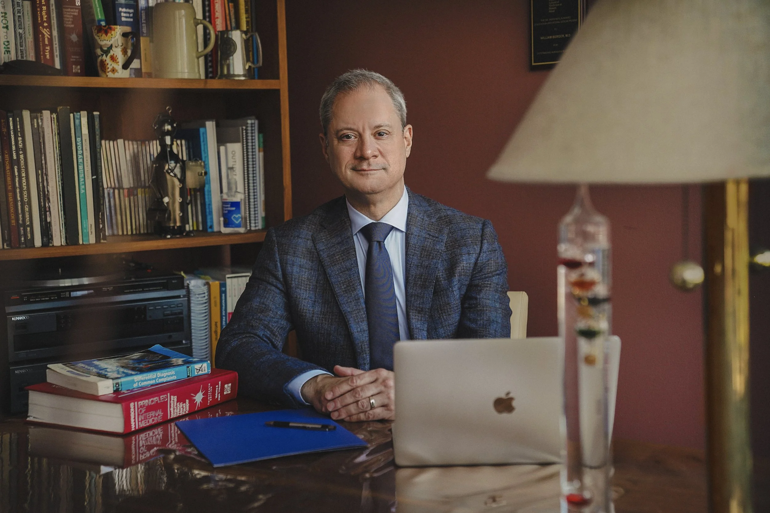 Dr. William Berger sitting in his offcie at northeast medical practice wearing blue suite and tie smiling to his patient on the other side.