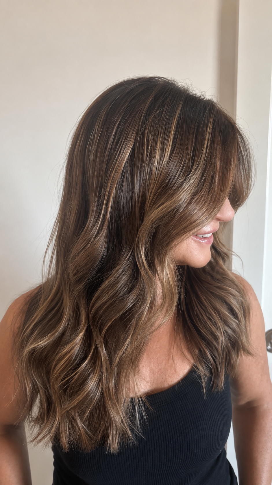 Mujer con cabello rubio de tonalidades marrones y reflejos, peinado con ondas suaves.