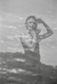 Black and white portrait of a woman standing beside water.