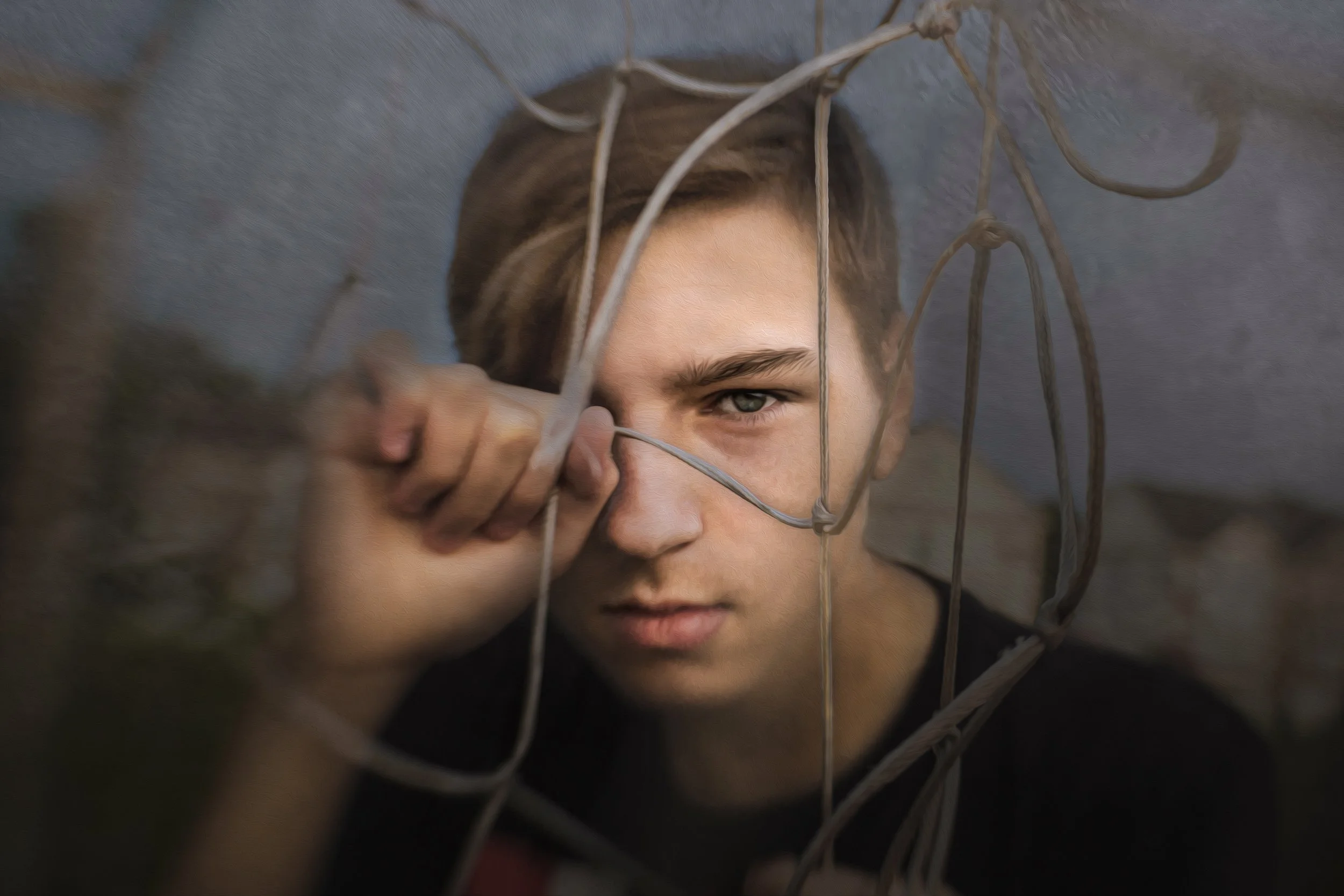 A young man  looking through a soccer net.