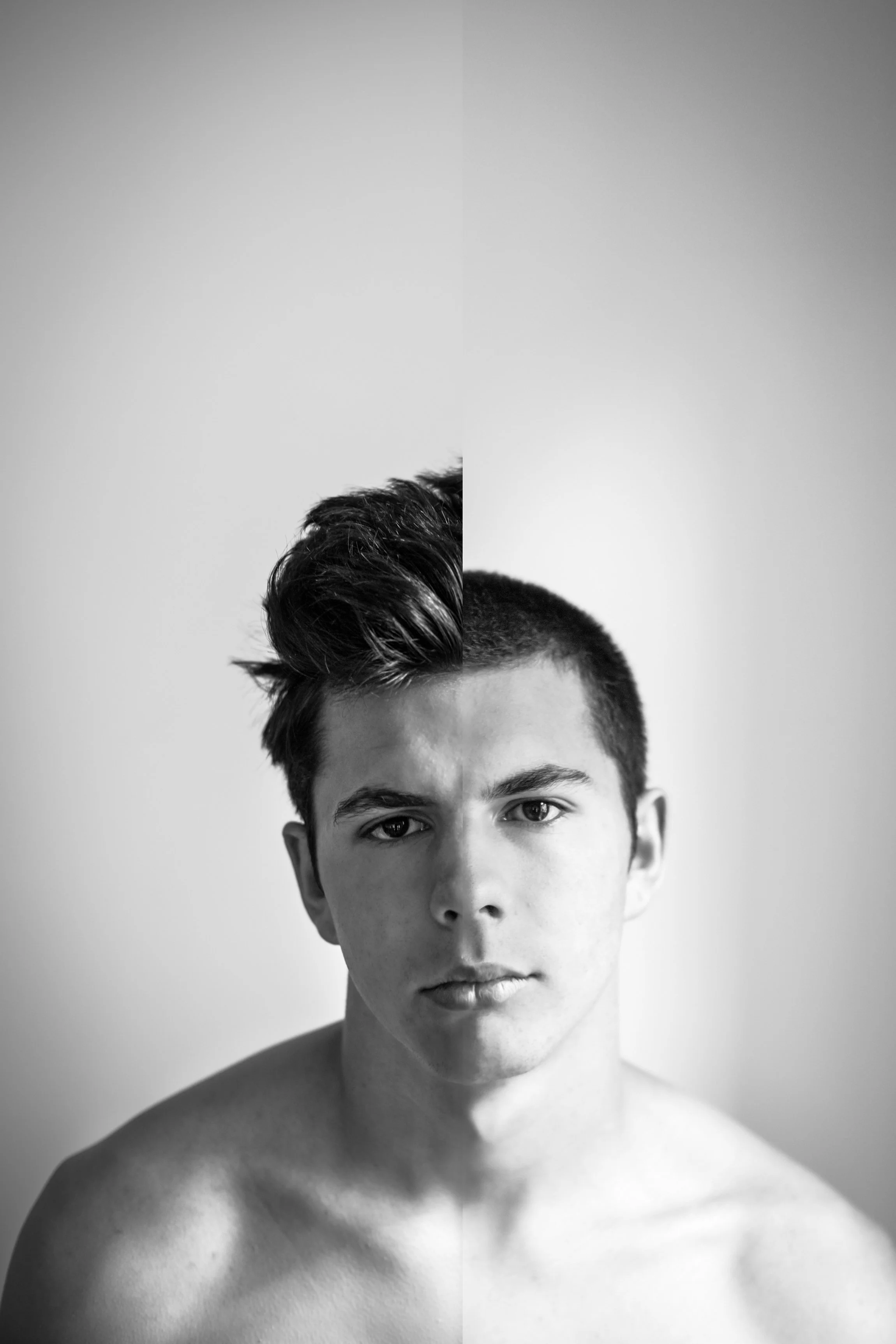 A black and white portrait of a young man with short hair, looking directly at the camera with a neutral expression.
