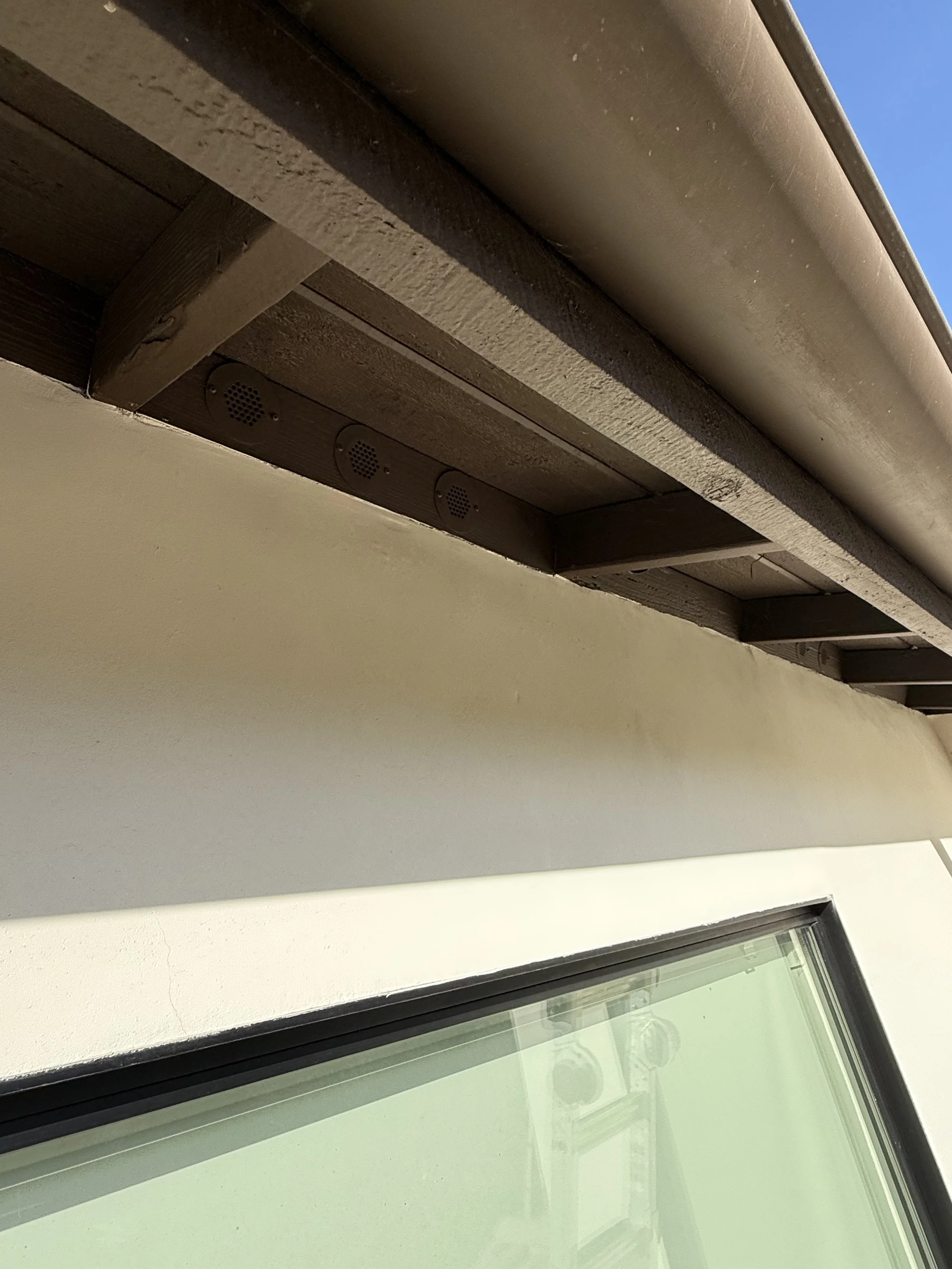 Image is of eaves that have been retrofitted against the threat of wildfire with BrandGuard vents round soffit eave vents and painted to match the home's exterior