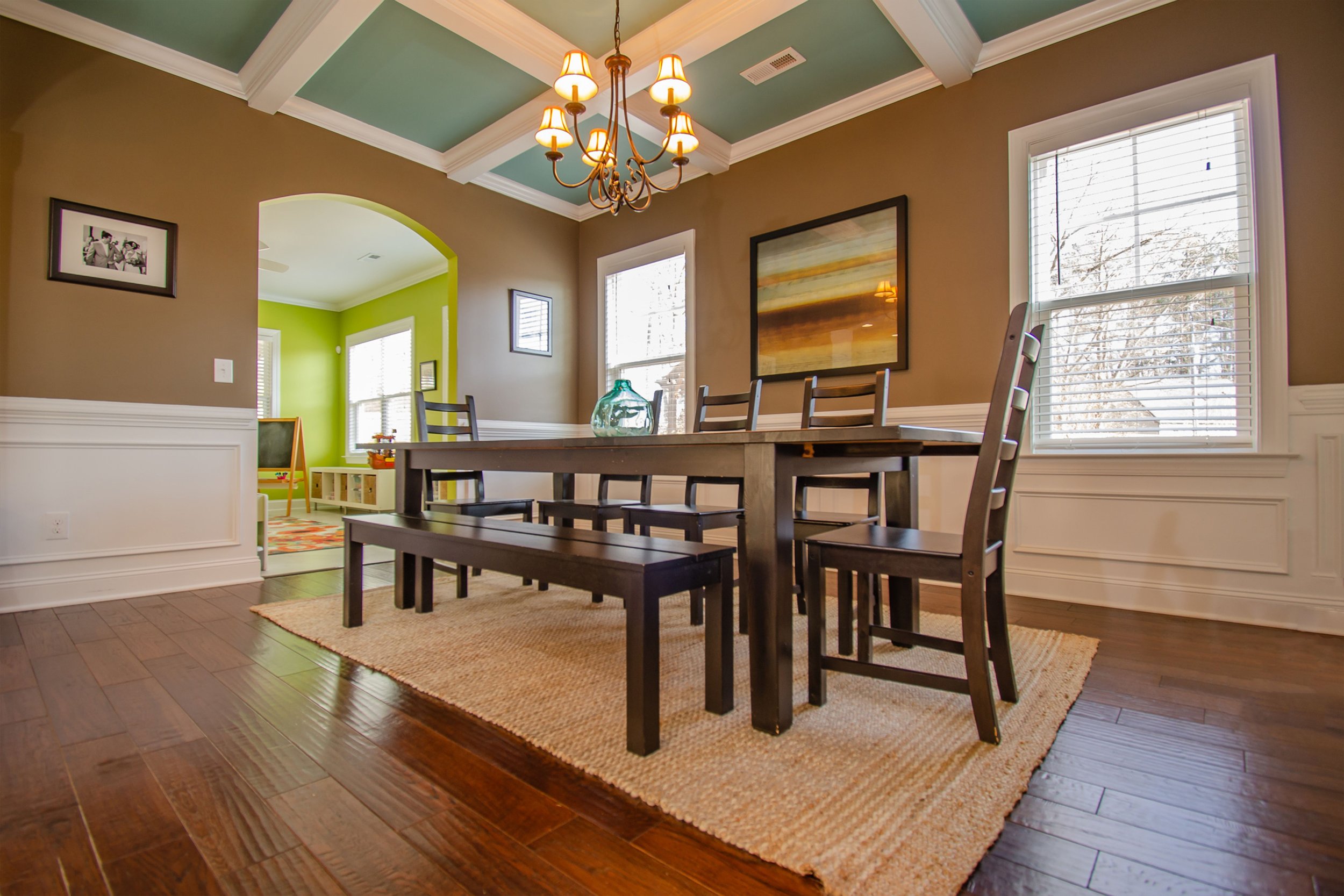 Dining room featuring crisp white picture-frame wainscoting, white crown molding, and two-tone coffered ceiling trim painting in a Clayton luxury residence.
