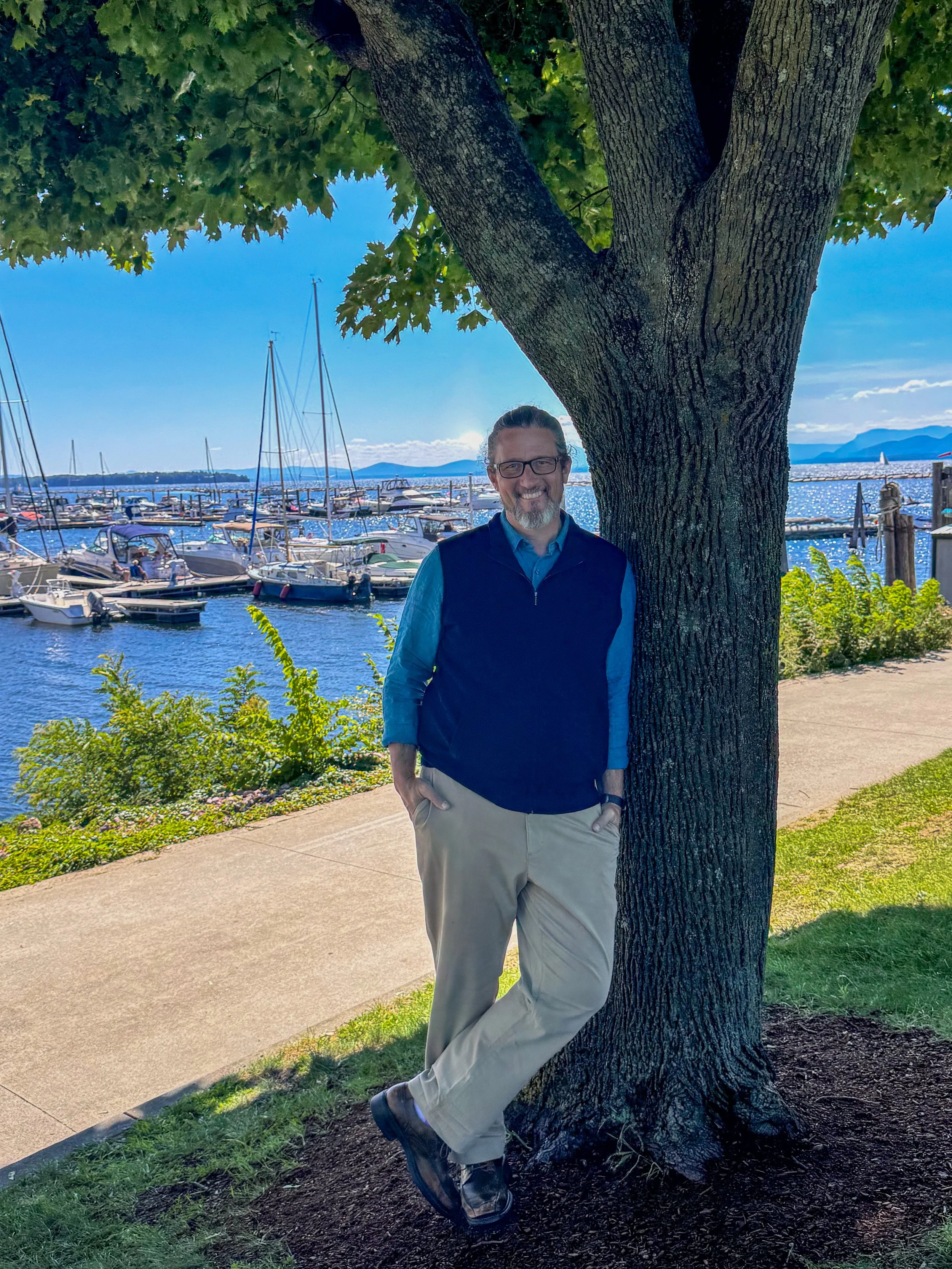 Derek Raynes standing beside a tree near Lake Champlain in Vermont.