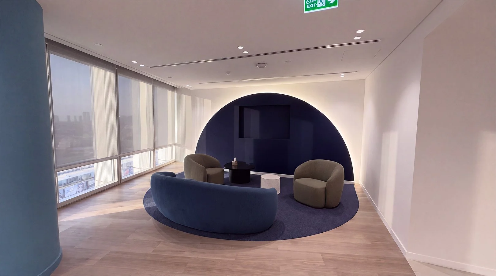 Campus lounge with a curved blue sofa, olive armchairs and a circular feature wall.