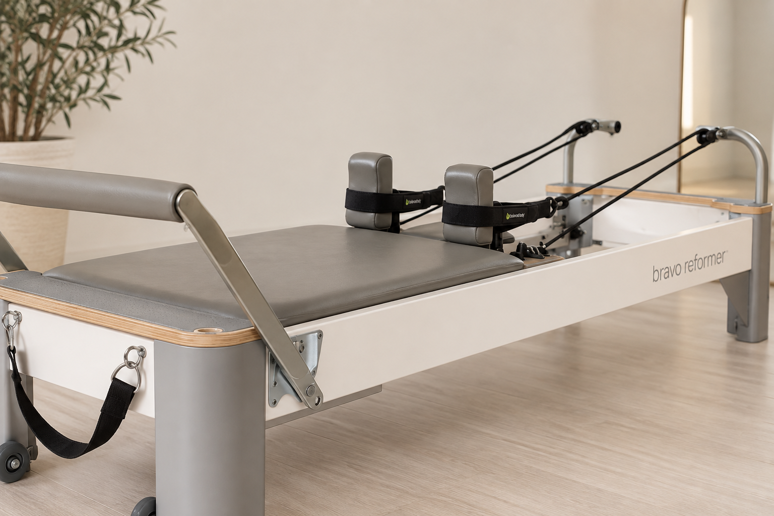 A medical reformer bed with attachments for physical therapy, including padded foot straps and adjustable resistance cords, in a clinical setting.