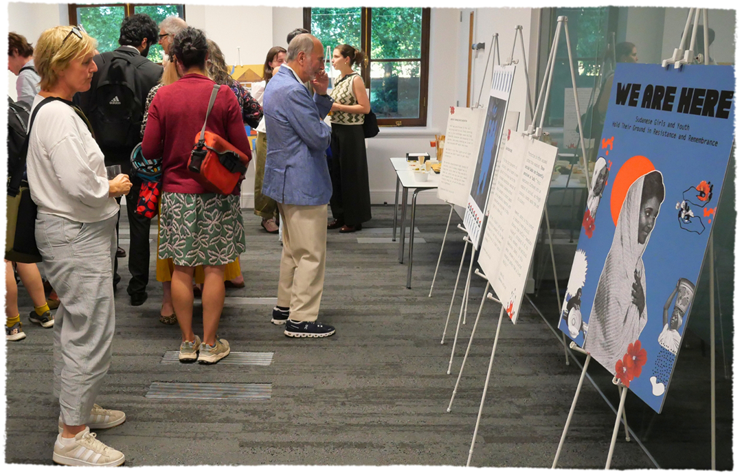 Visitors view a gallery exhibition featuring posters about Sudanese girls and youth, resistance, and remembrance.