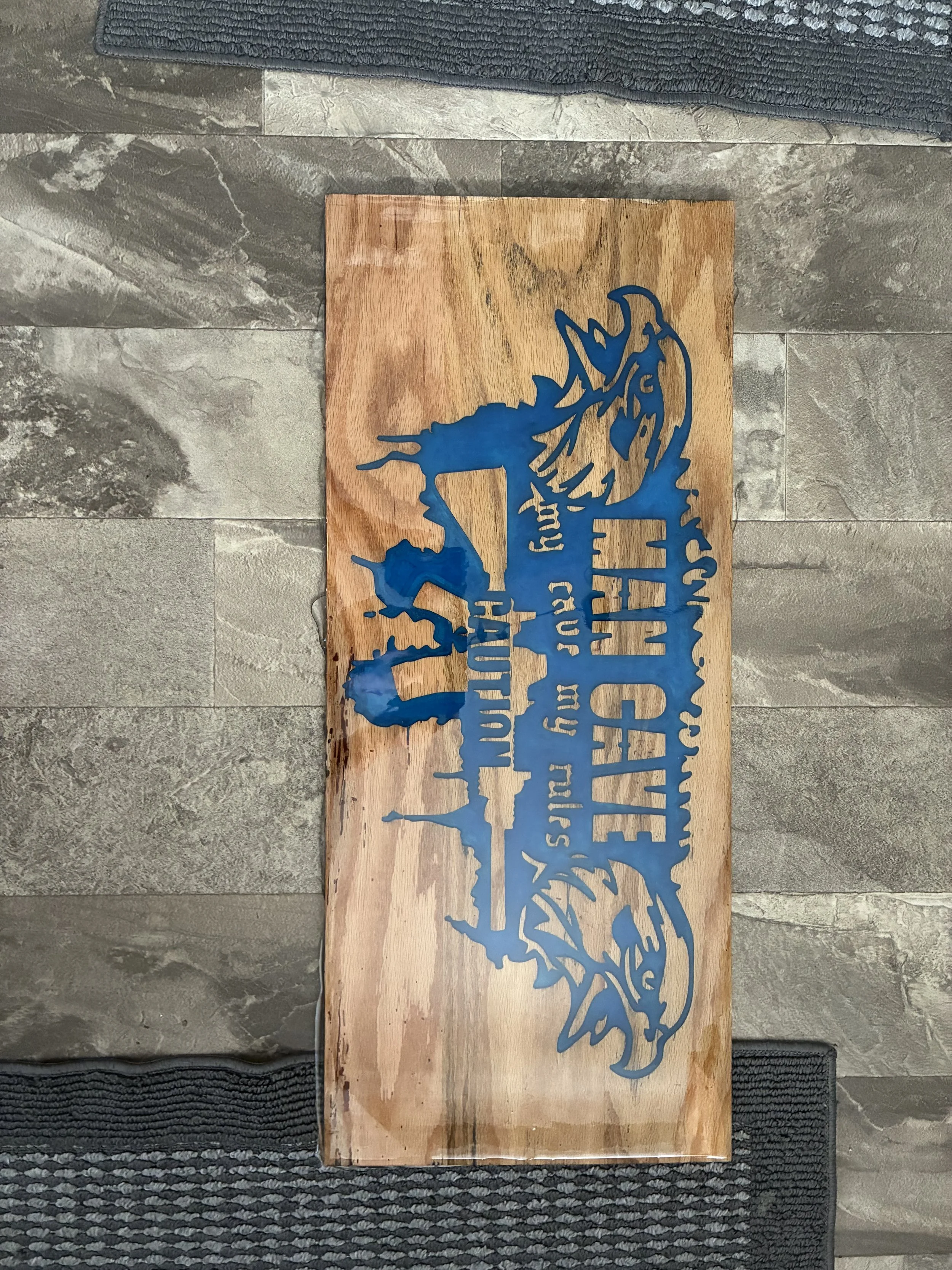A wooden sign with a blue silhouette of a deer and the text 'Welcome to the Forest' on a tiled floor.