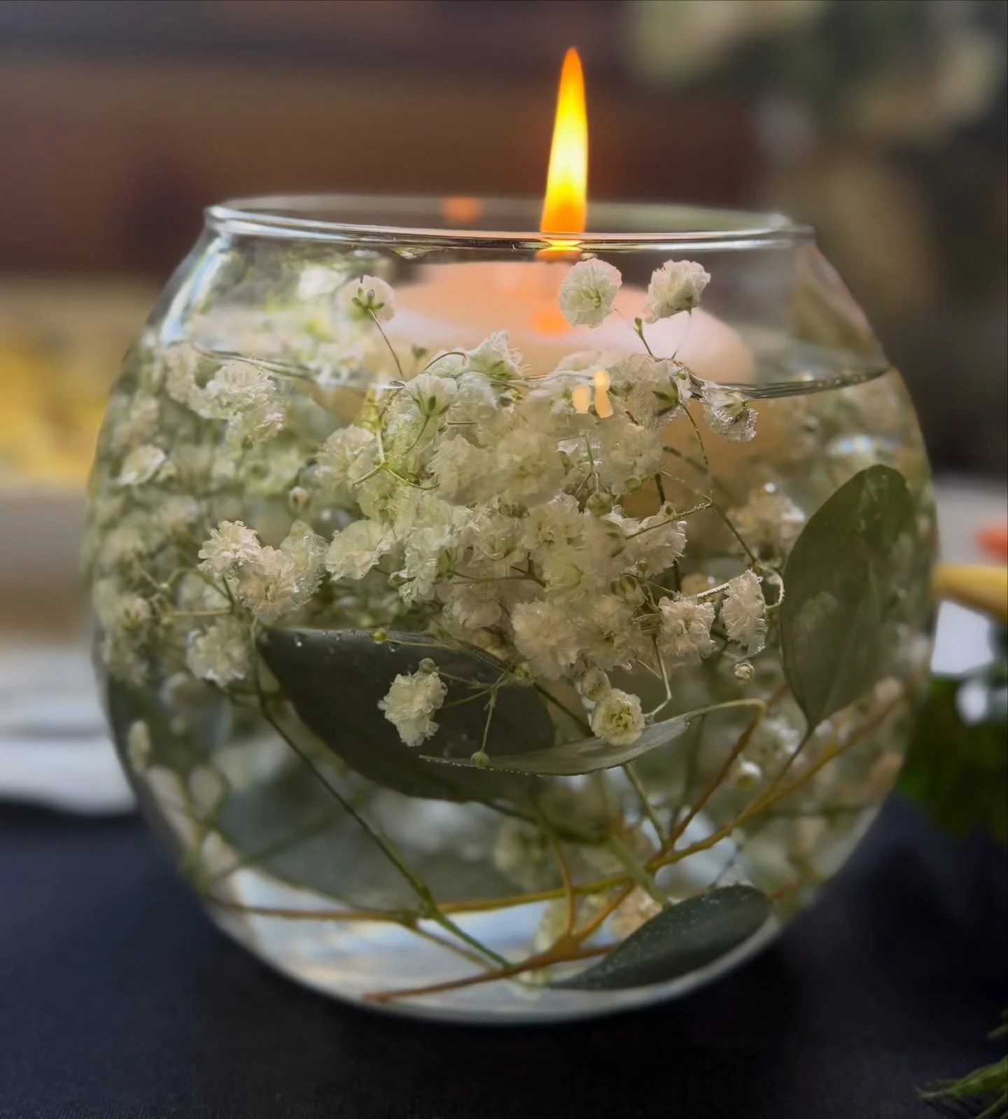 Floating candle and white baby's breath flowers in a round glass bowl