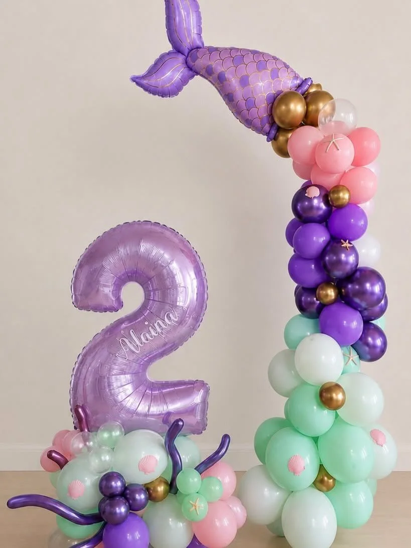 Under-the-sea themed balloon display with a purple mermaid tail, number two balloon, and pastel balloon garlands