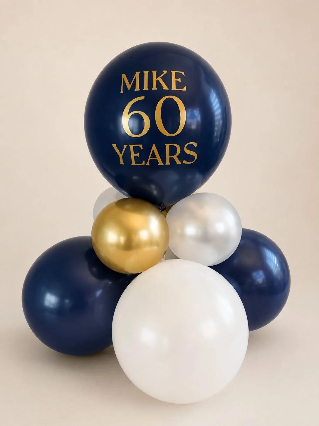 Navy blue, gold, and white balloon arrangement featuring a large balloon labeled “Mike 60 Years.”