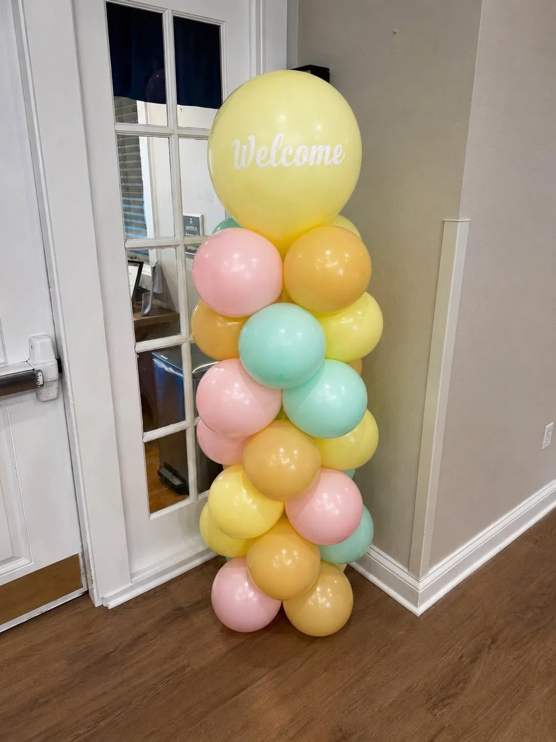Pastel balloon column with a large yellow “Welcome” balloon at a home entryway