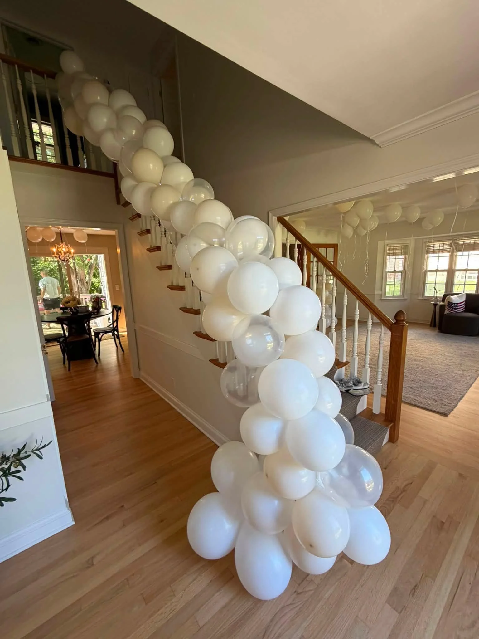 White balloon garland decorating a wooden staircase in a bright home entryway