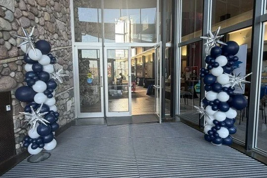 Navy blue, white, and silver balloon columns framing a glass building entrance