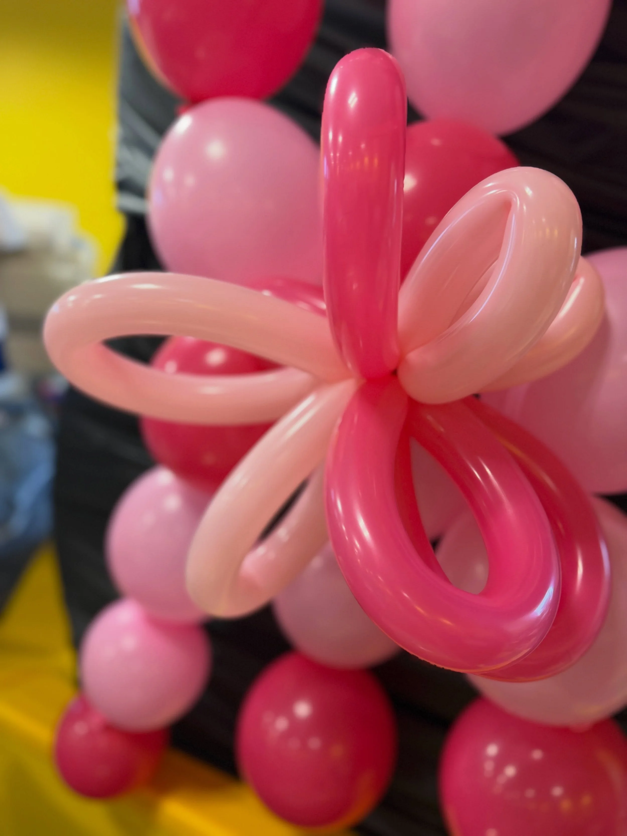Close-up of glossy pink and red intertwined balloon loops against a colorful background