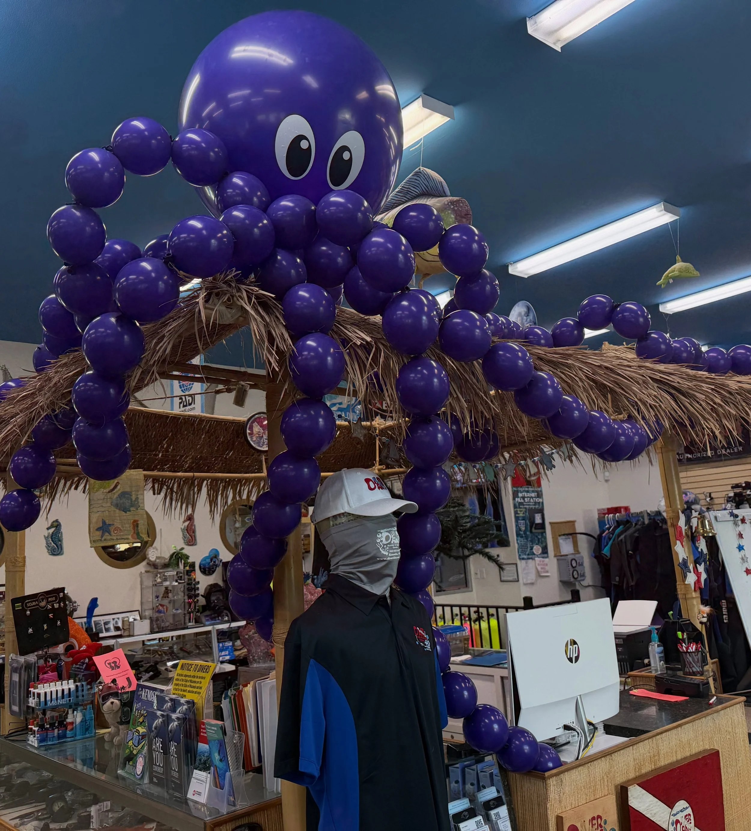 Purple balloon octopus decoration hanging above a souvenir shop counter with a person standing beneath it